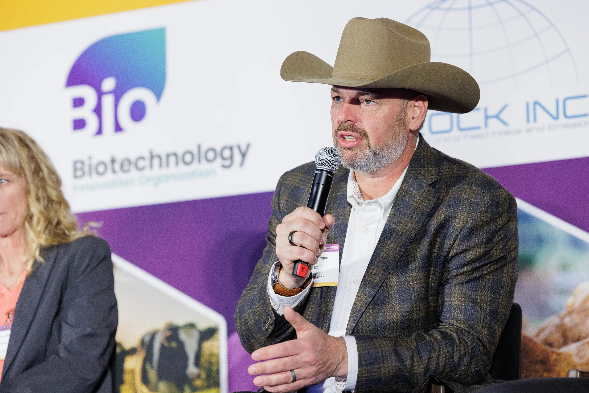 Panelist wearing cowboy hat gestures while speaking into microphone at Orlando summit