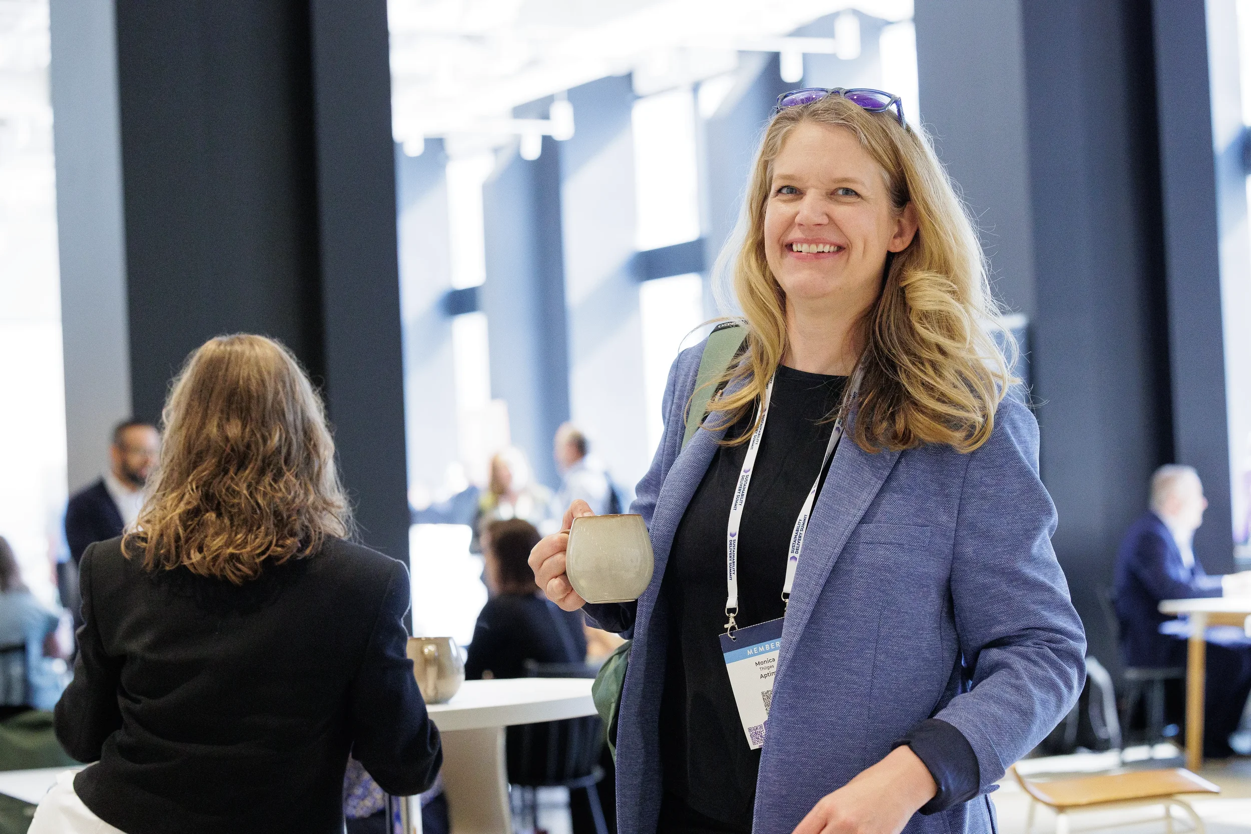 Attendee holds coffee mug while smiling during conversation at Chicago corporate conference
