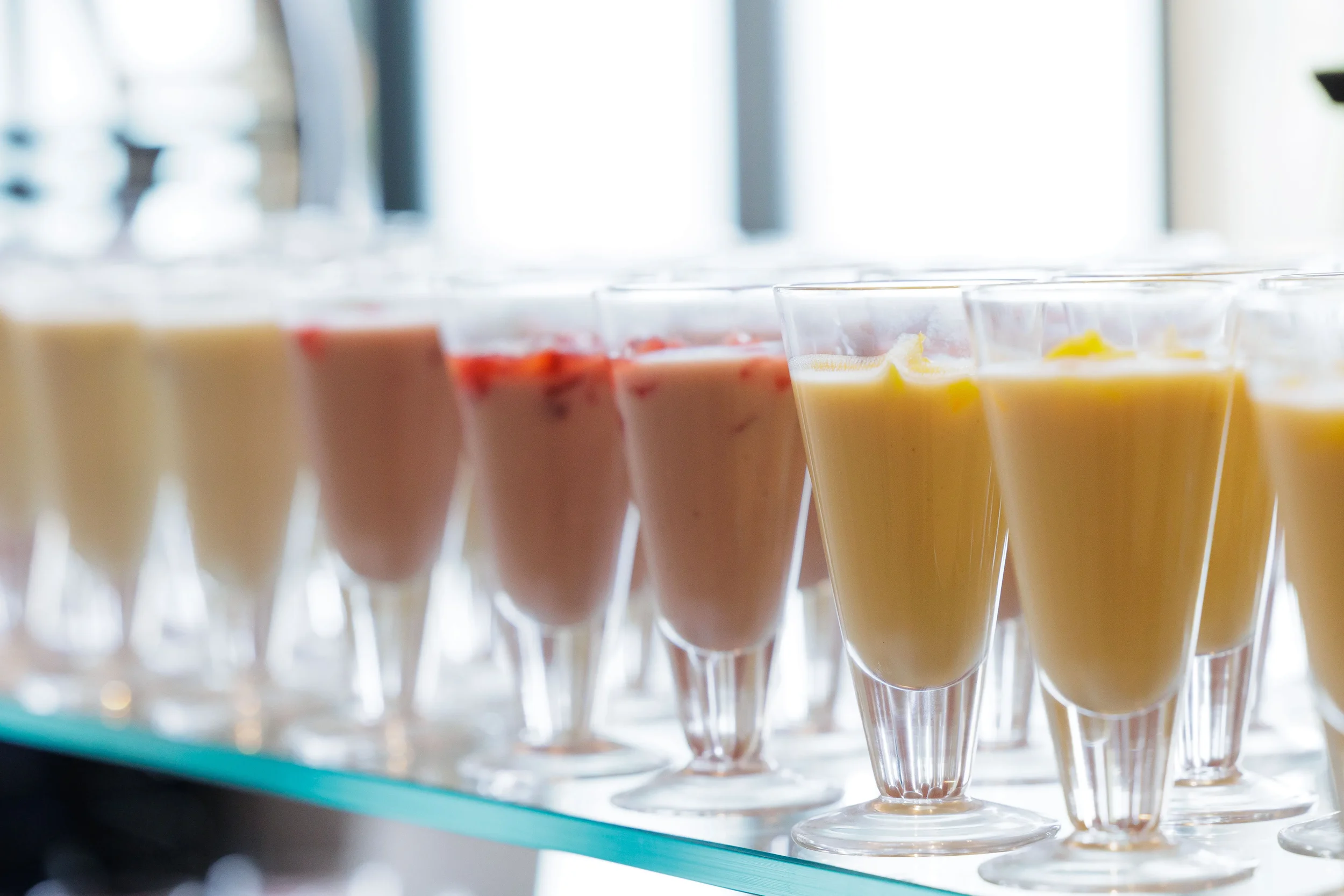 Rows of colorful fruit smoothie drinks lined up in glasses at Chicago corporate conference catering display