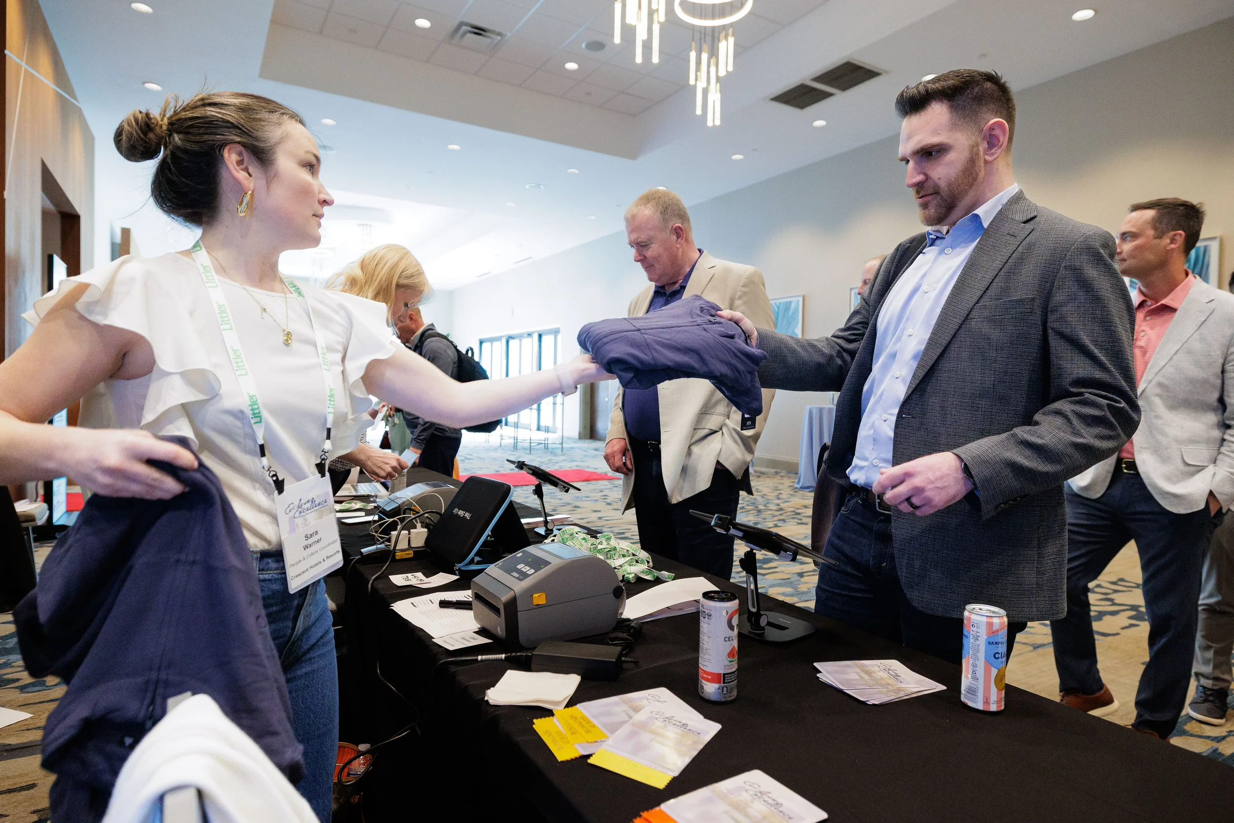 Staff member hands shirt to attendee across registration table at Orlando corporate conference