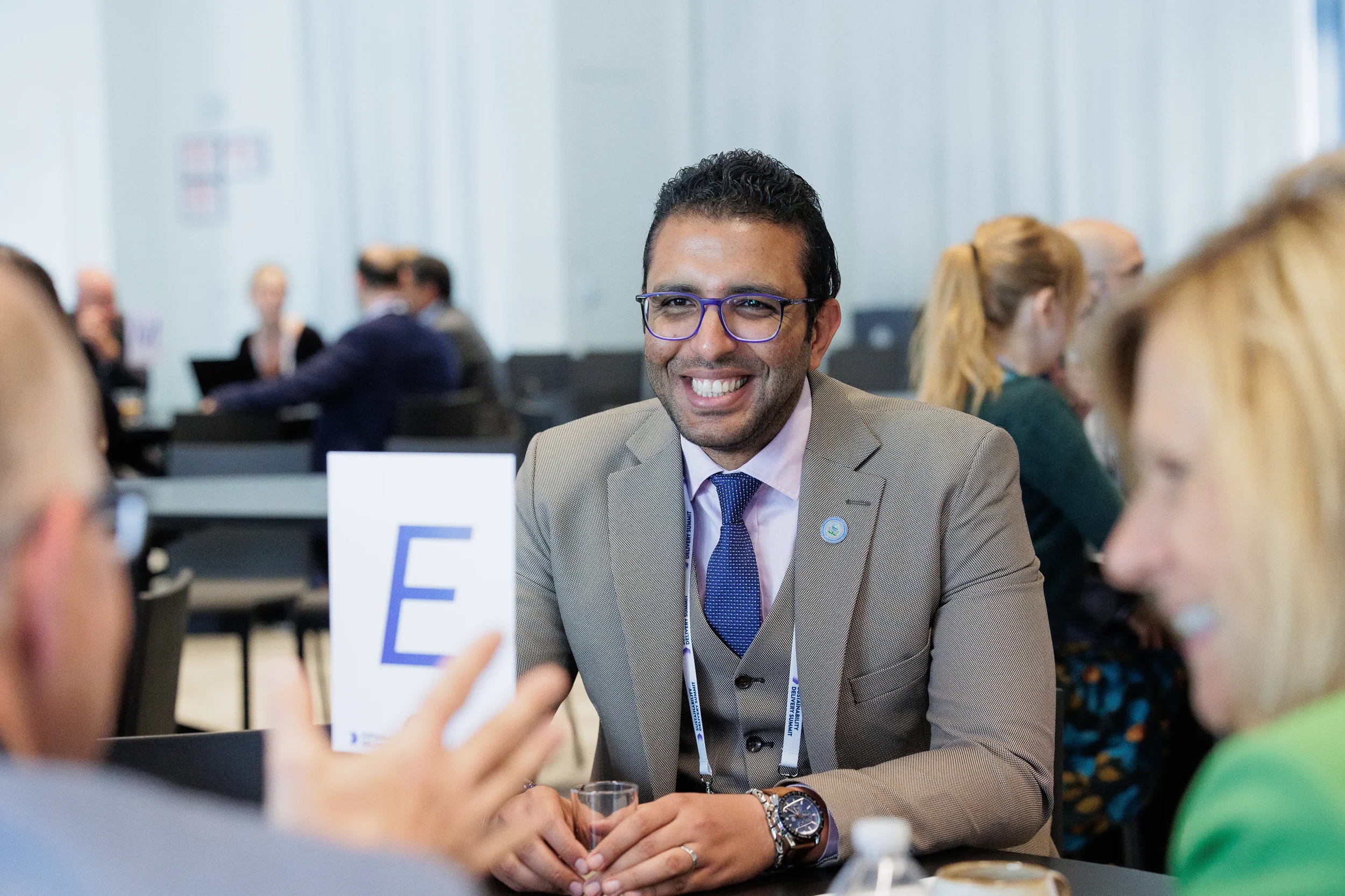 Attendee smiles while networking at table during break at Chicago industry conference