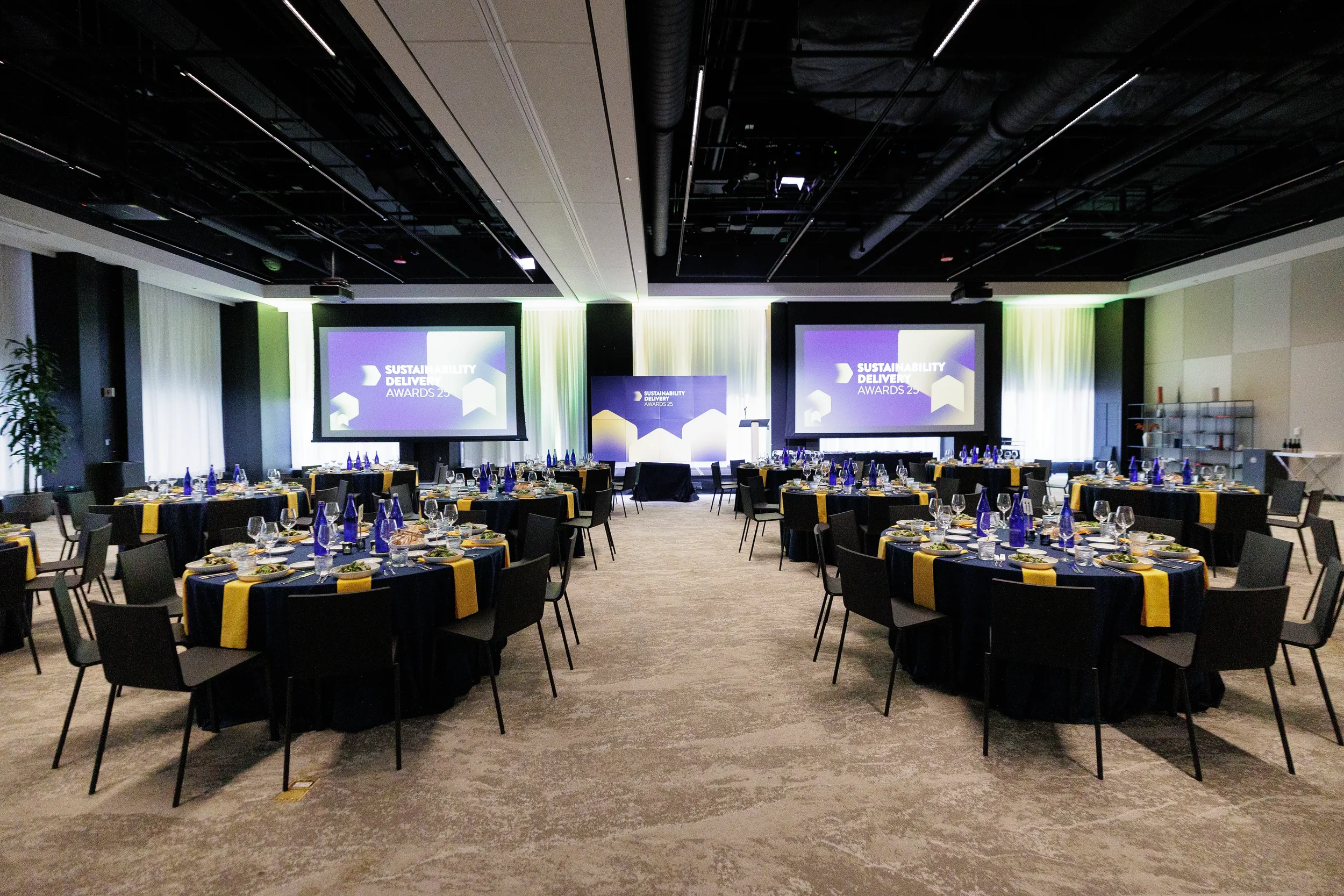 Ballroom set with round tables and dual screens ahead of Chicago corporate awards event