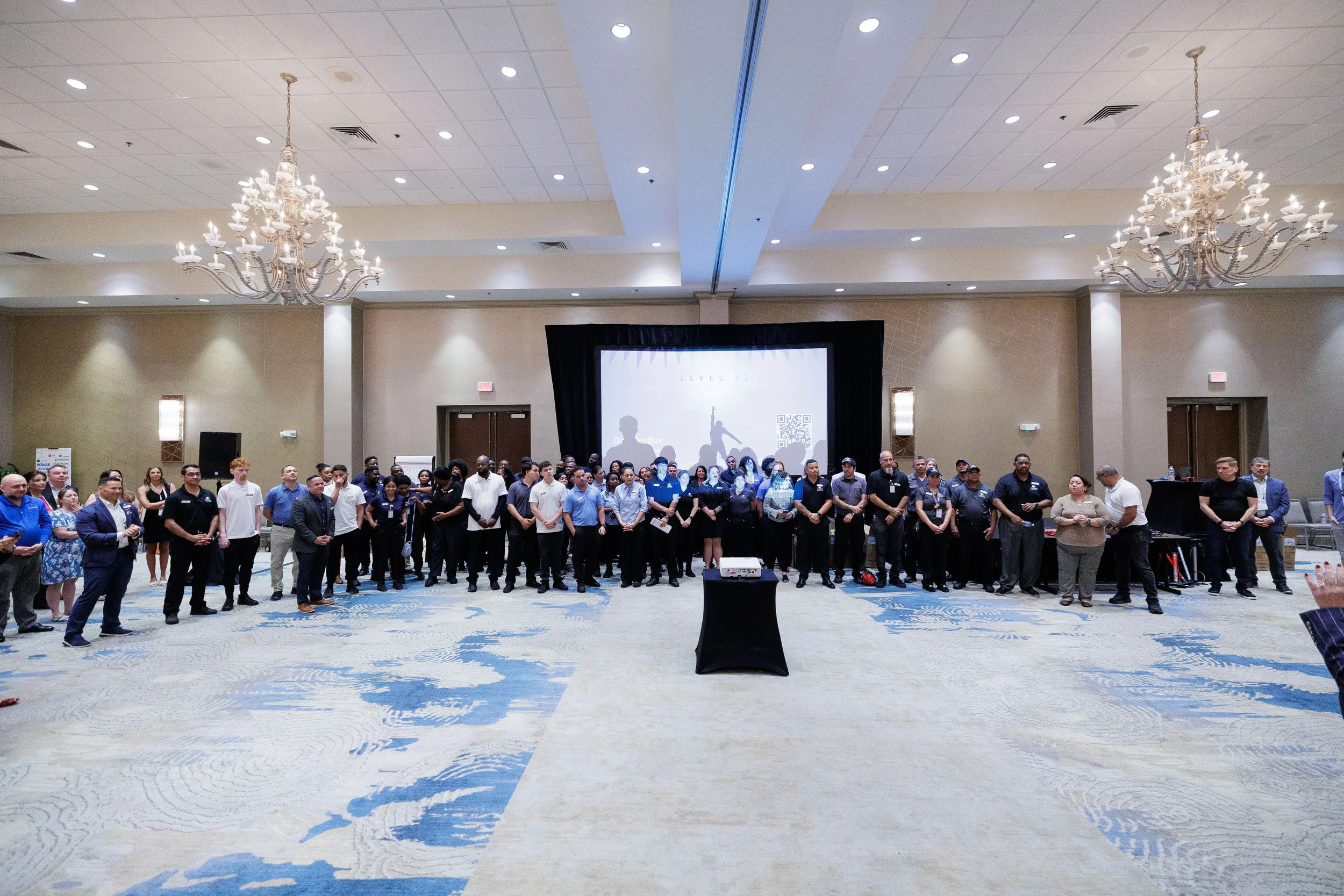 Large group of conference attendees gathered in chandelier ballroom in front of projection screen in Chicago