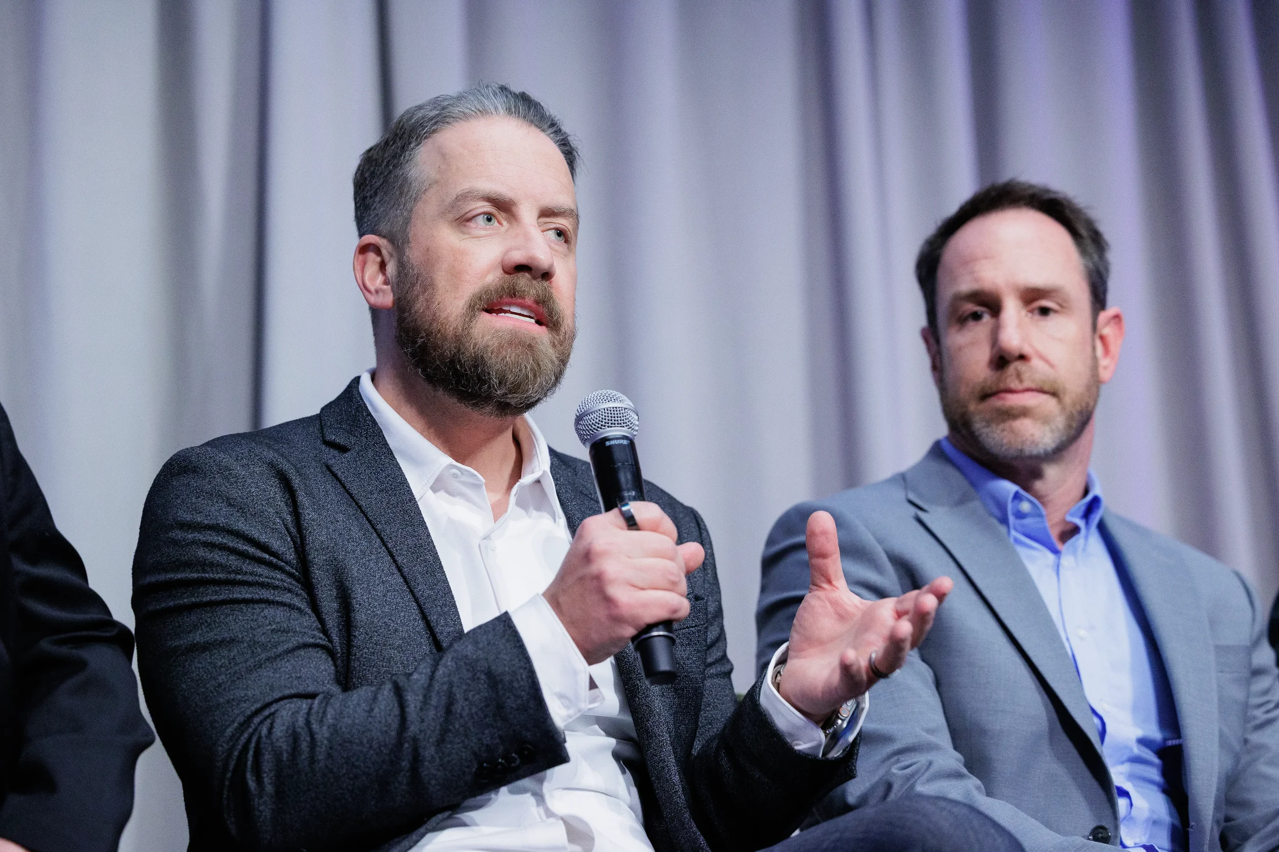 Panelist speaks into microphone while fellow speaker listens at Chicago industry conference