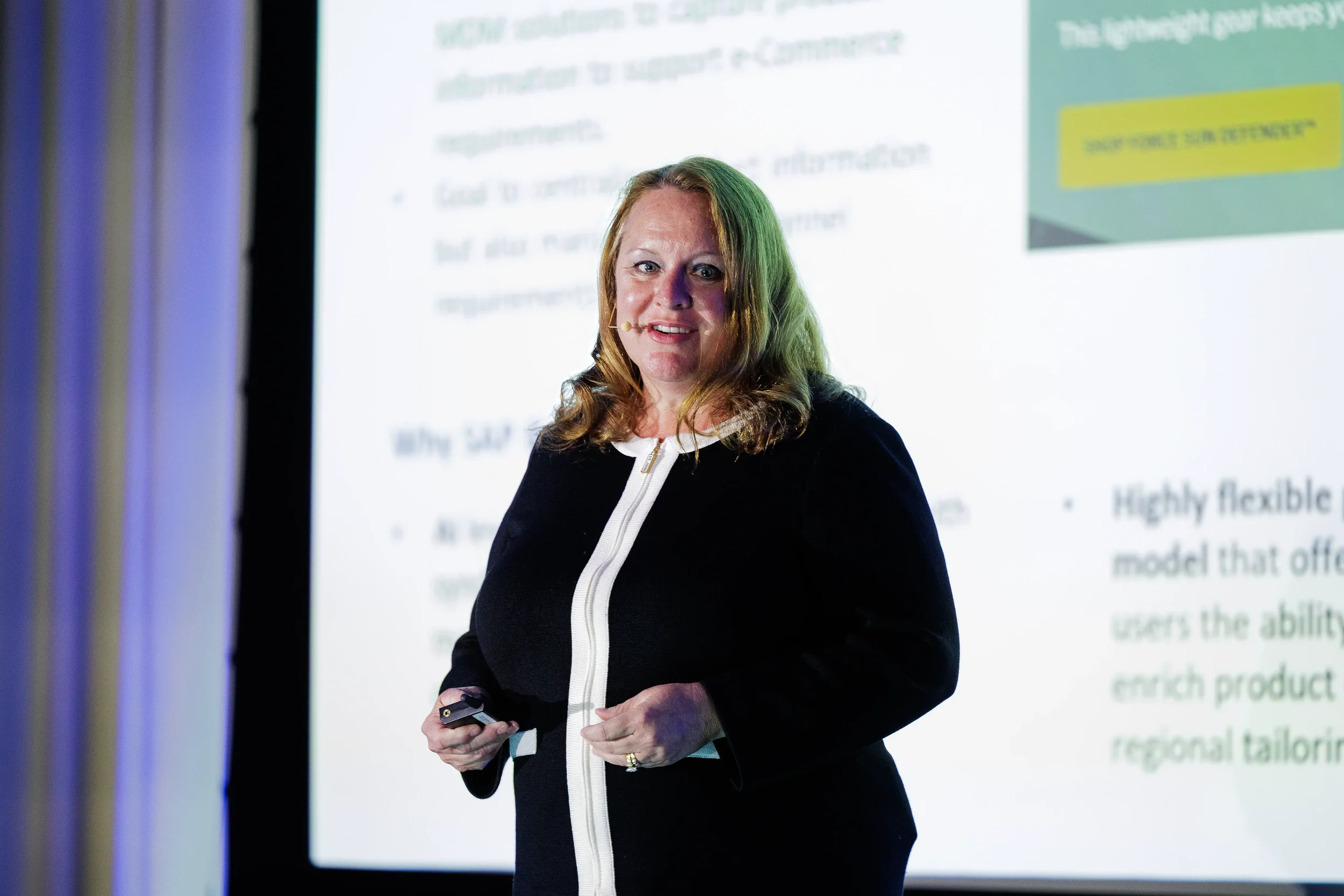 Smiling speaker with headset microphone presents slides on stage at Orlando corporate conference