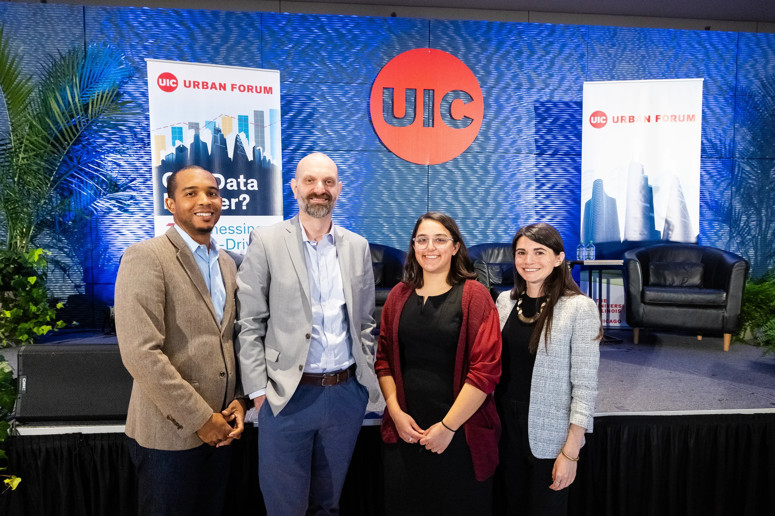 Four speakers pose together for photo in front of branded stage at Chicago industry conference