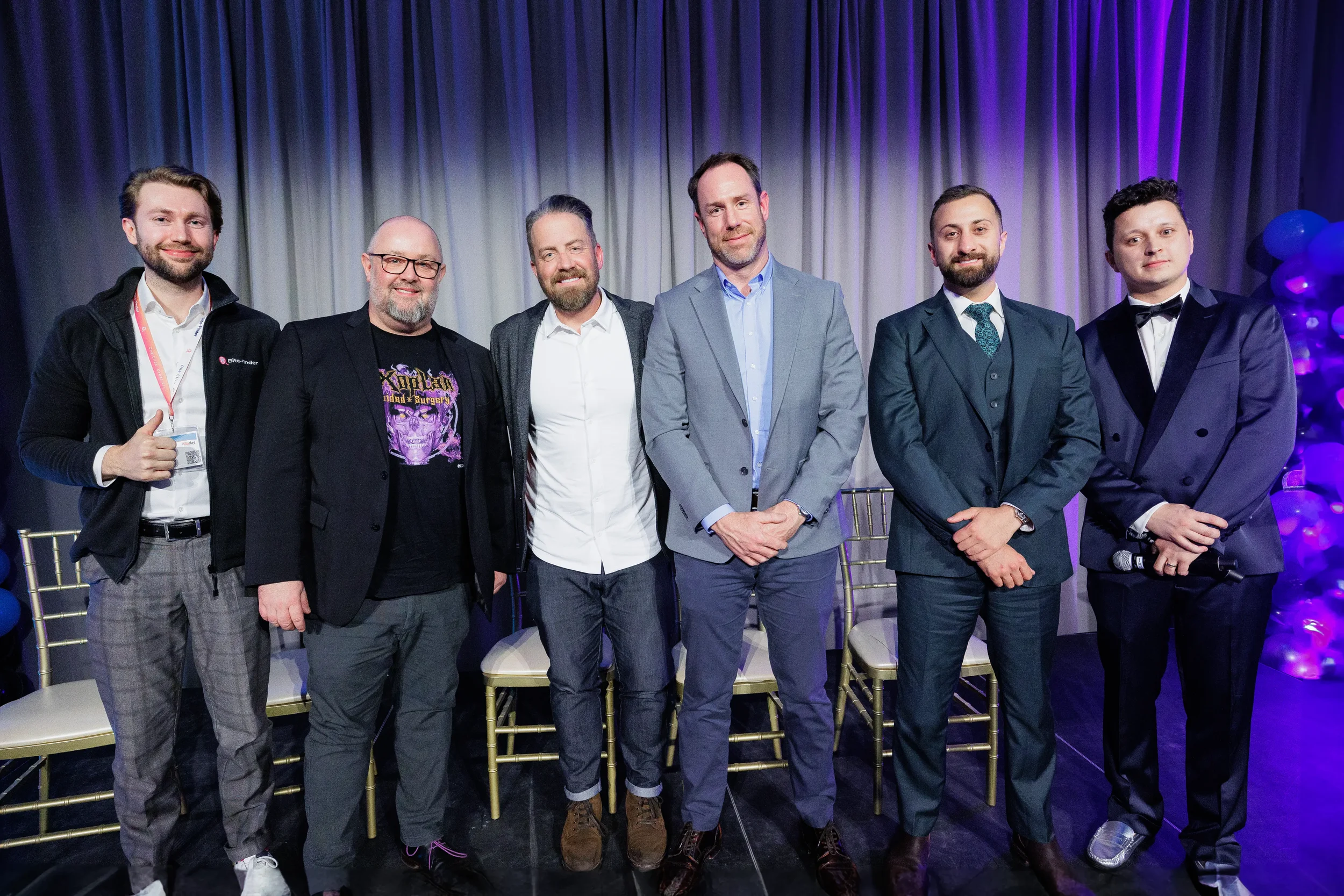 Six panelists and emcee pose together for photo on stage at Orlando industry conference