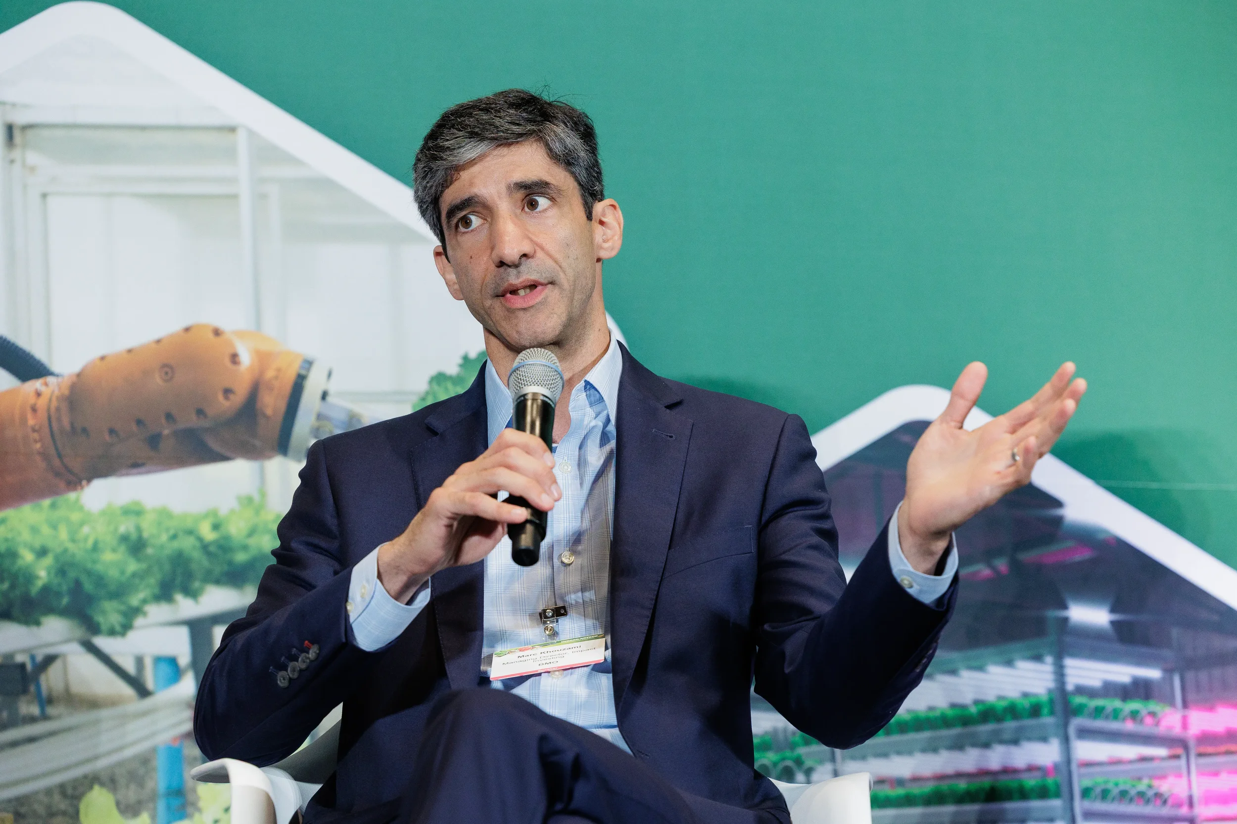 Panelist speaks with both hands raised expressively in front of green branded backdrop at Orlando industry conference