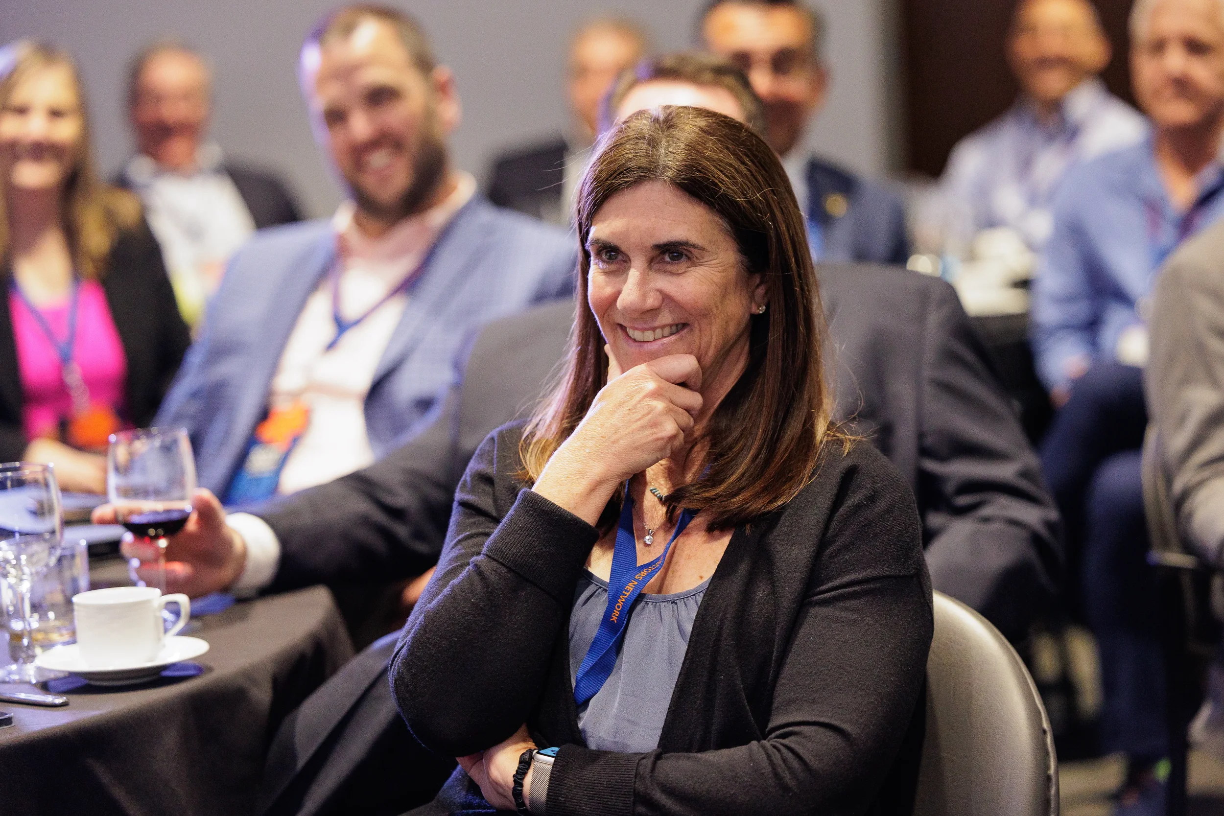 Female attendee with lanyard smiles warmly while seated at Chicago corporate conference evening event