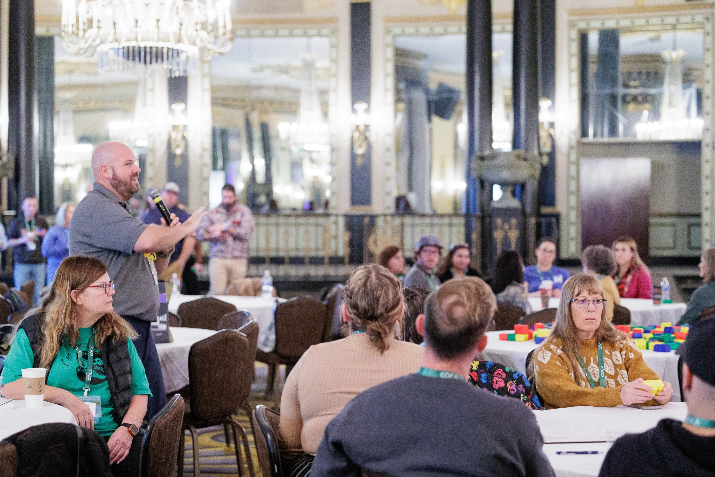 Speaker addresses seated audience with microphone in ornate ballroom at Chicago nonprofit conference event