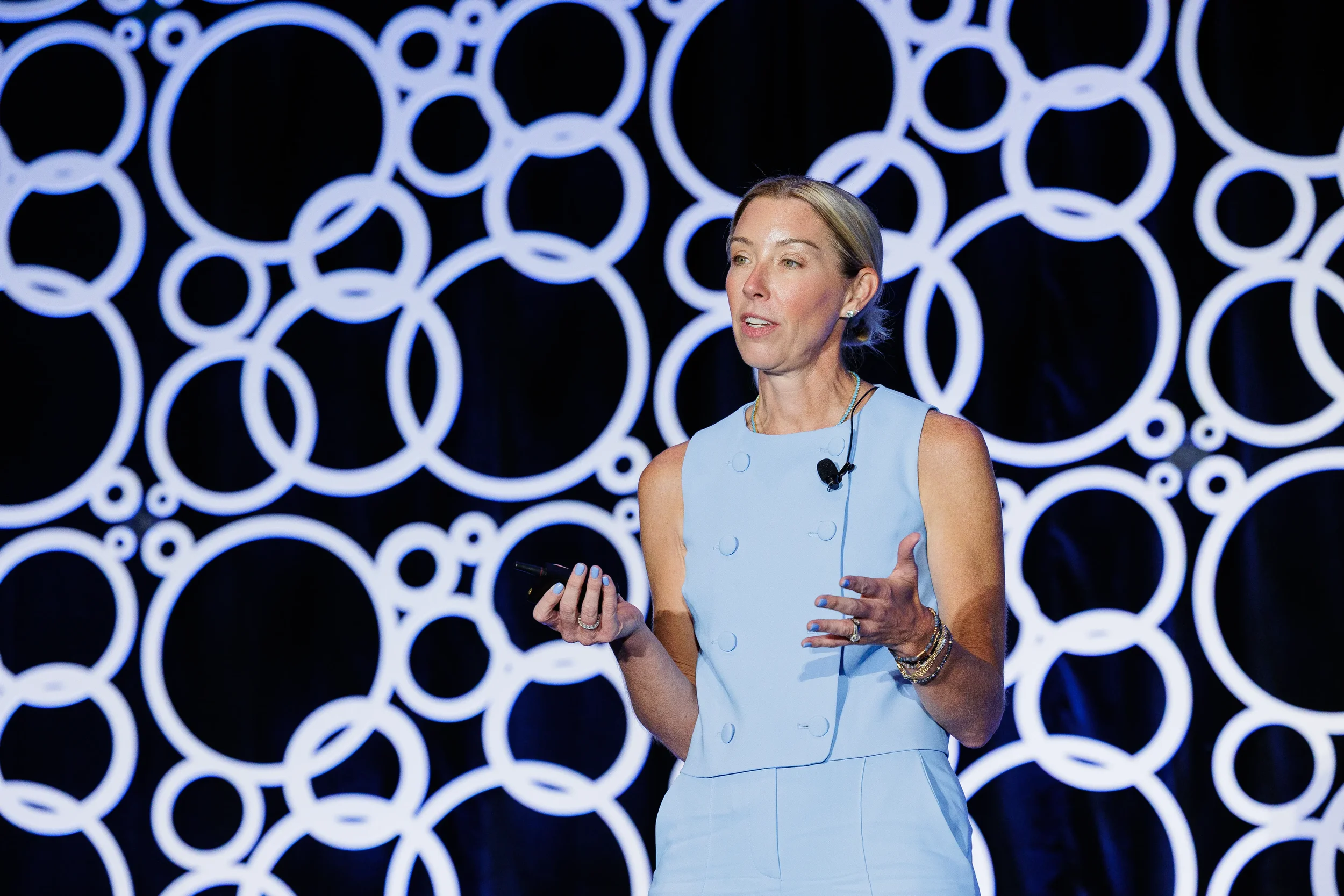 Speaker presents on stage with illuminated circular backdrop at Chicago industry conference