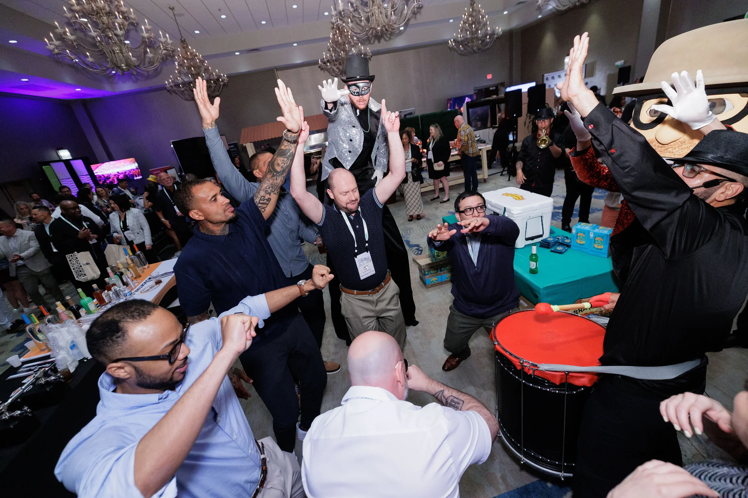 Attendees dance energetically with stilt performer and drummer at Orlando industry conference reception