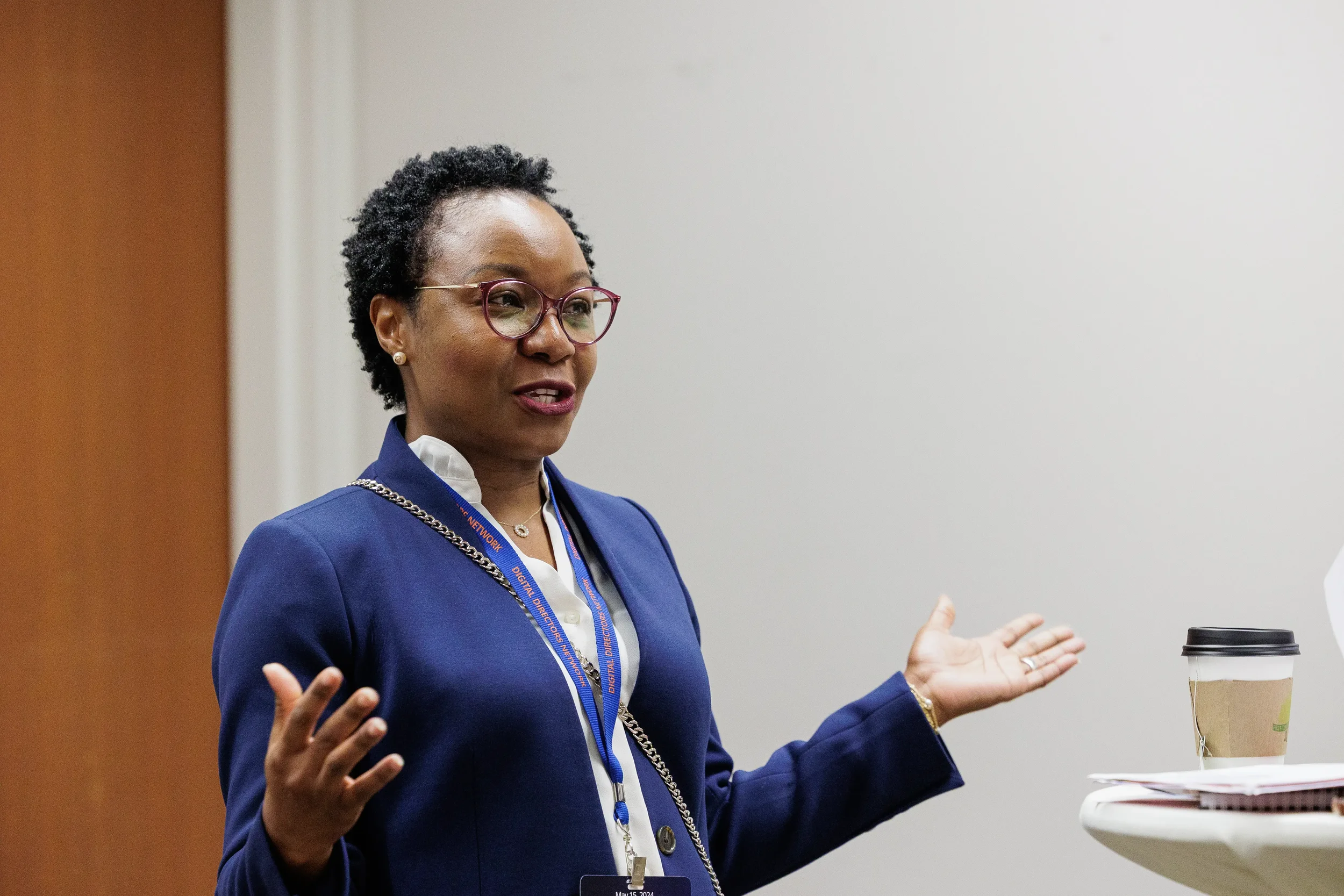 Female speaker with lanyard gestures with both hands while presenting at Chicago corporate conference