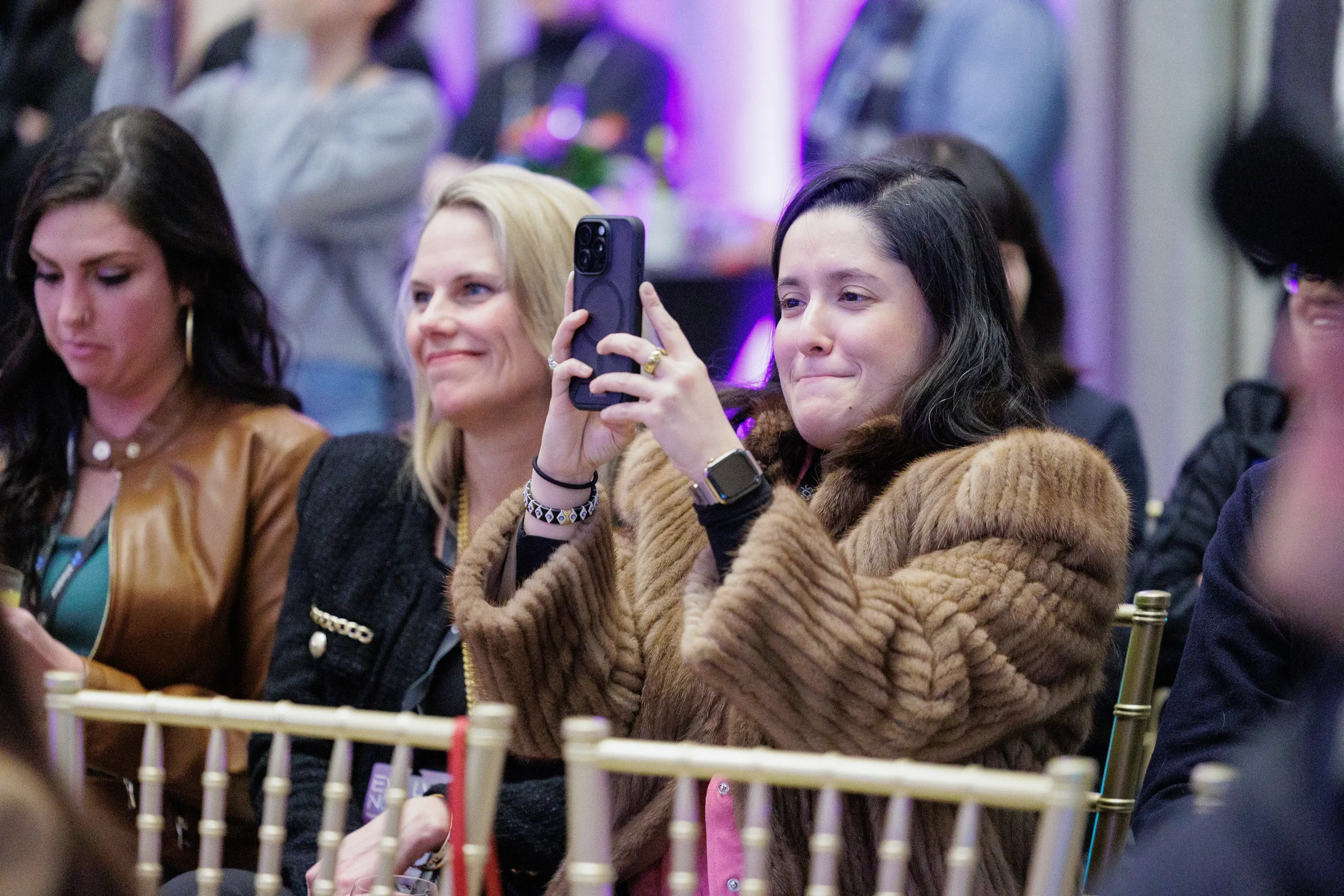 Attendee photographs the stage with her phone during session at Orlando corporate event