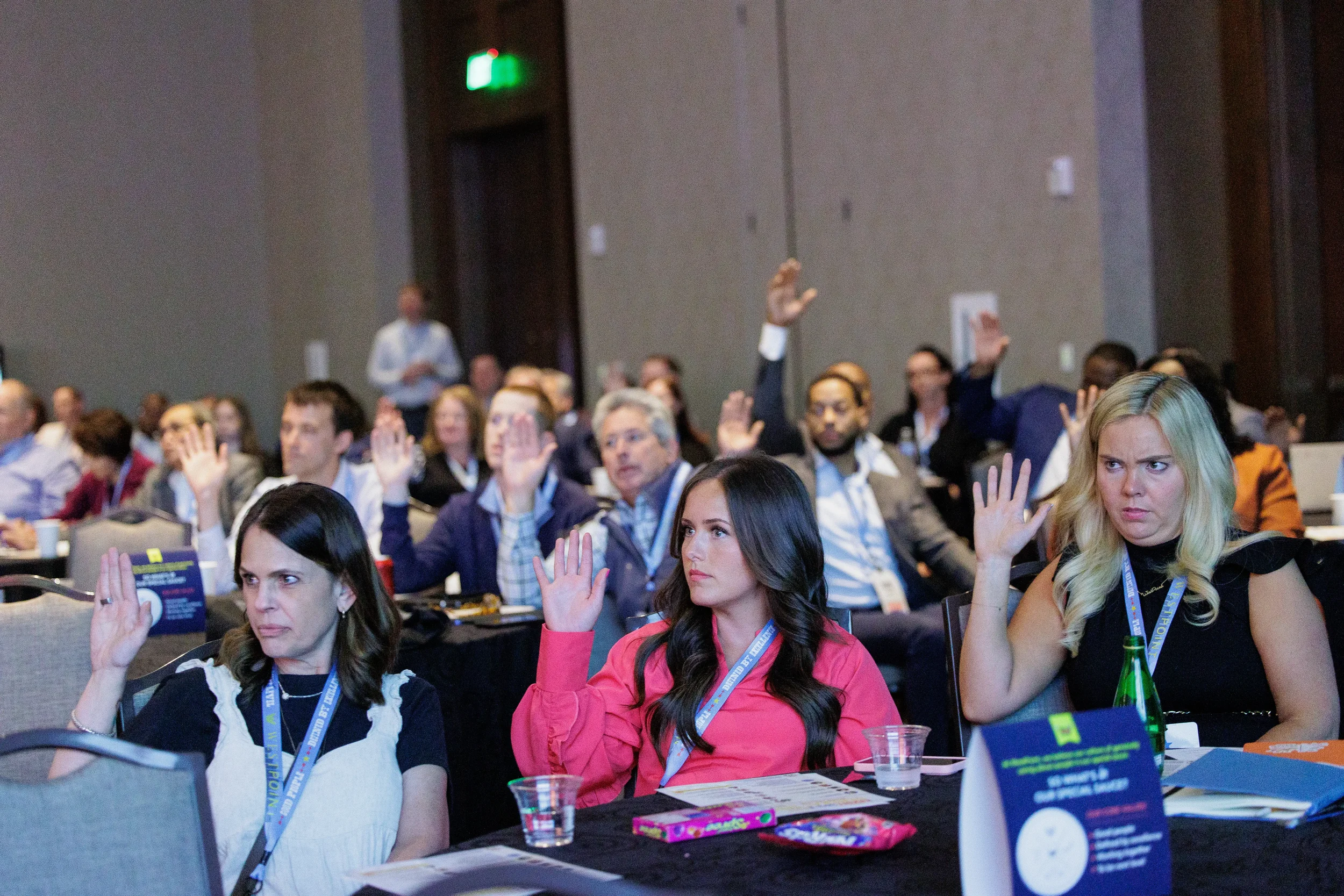Conference attendees raise hands to respond during interactive session at Orlando corporate event