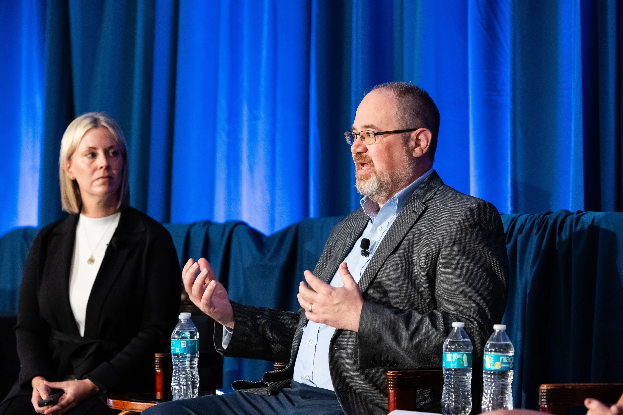 Panelist gestures while speaking during discussion on stage at Orlando industry conference