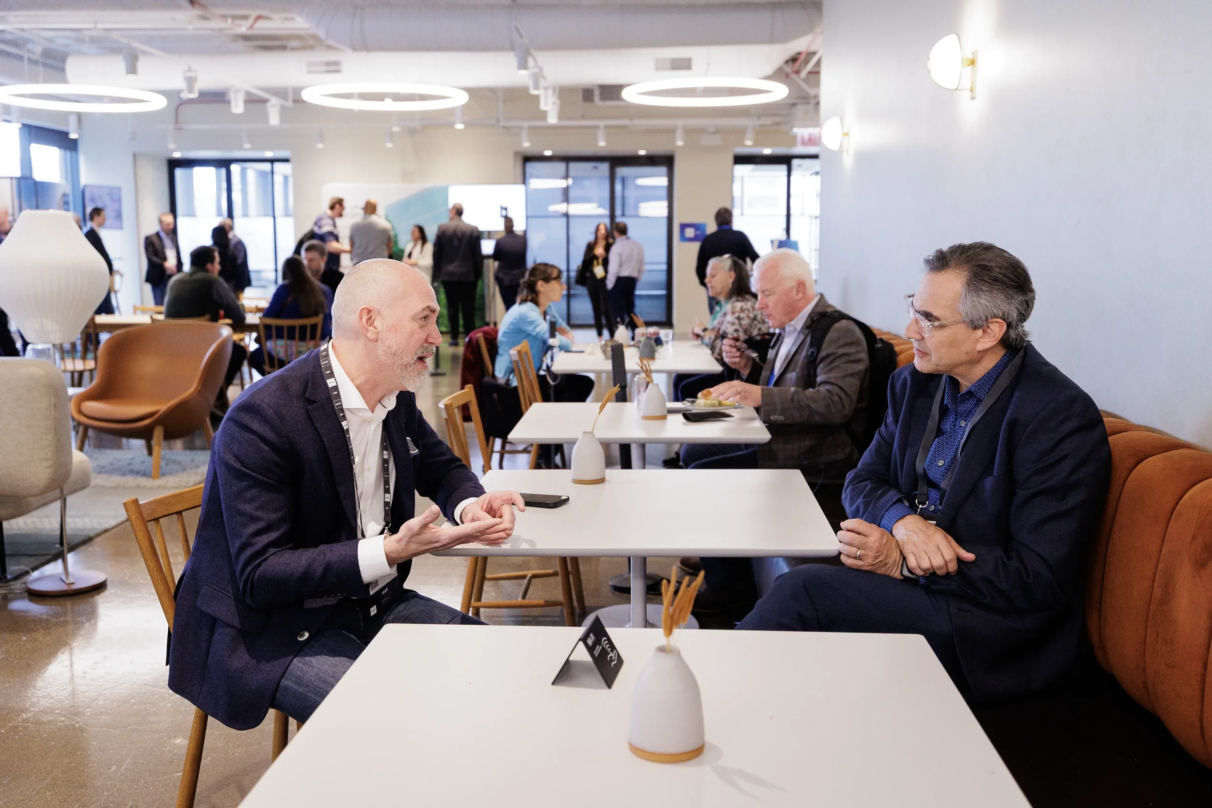 Two attendees talk over lounge tables during networking break at Chicago industry conference
