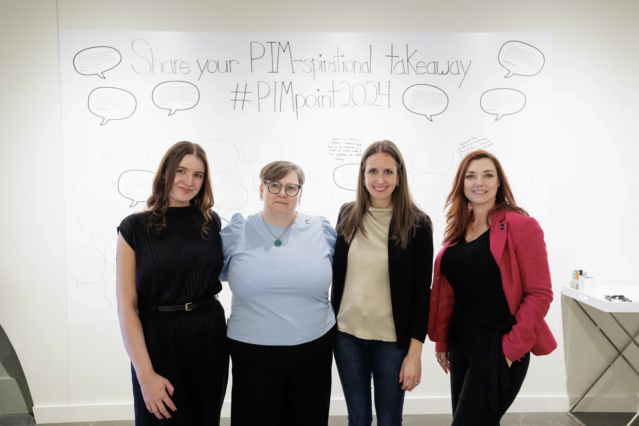 Four colleagues pose together in front of interactive feedback wall at Chicago industry conference