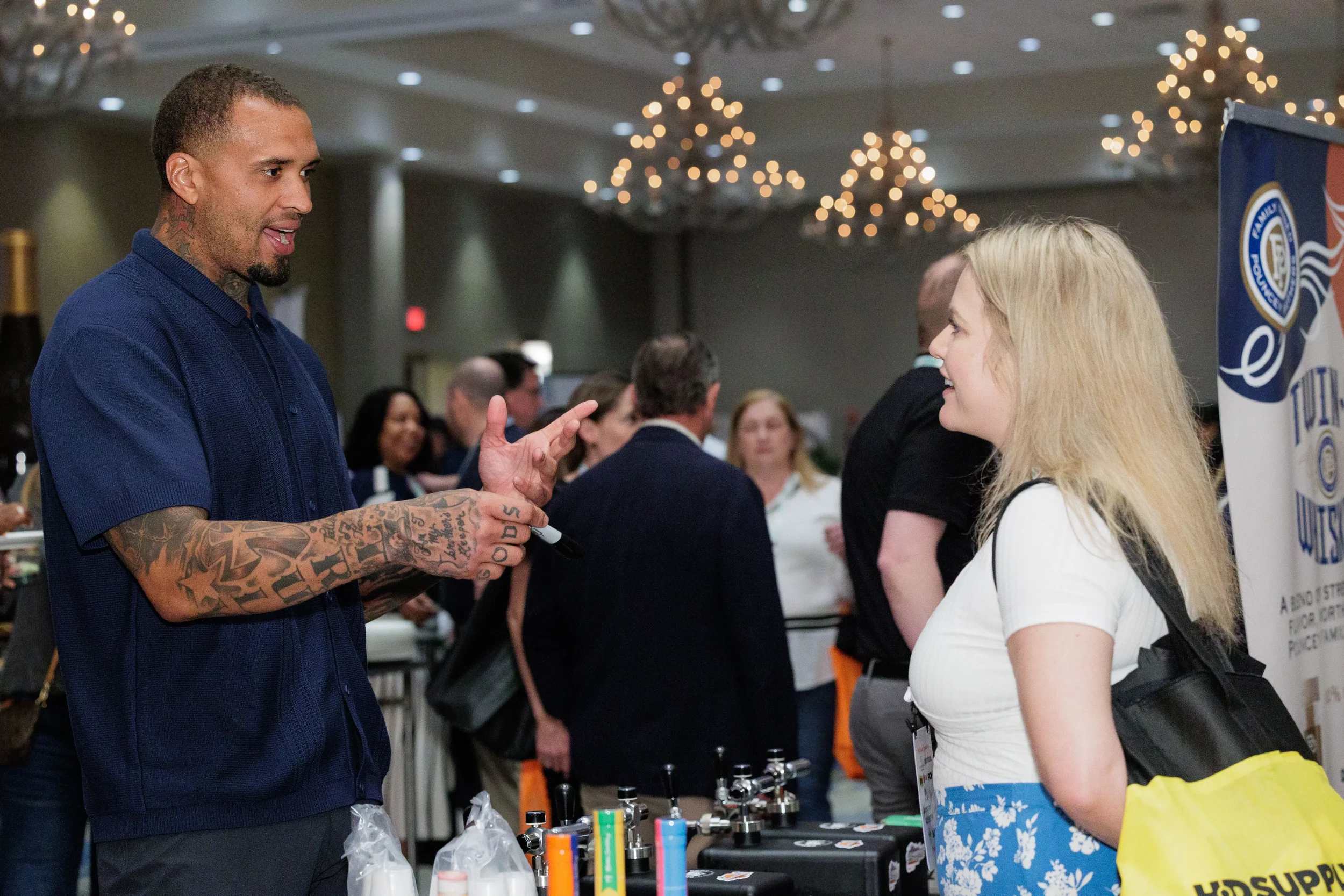 Exhibitor gestures while speaking with attendee at sponsor booth during Chicago corporate conference trade show