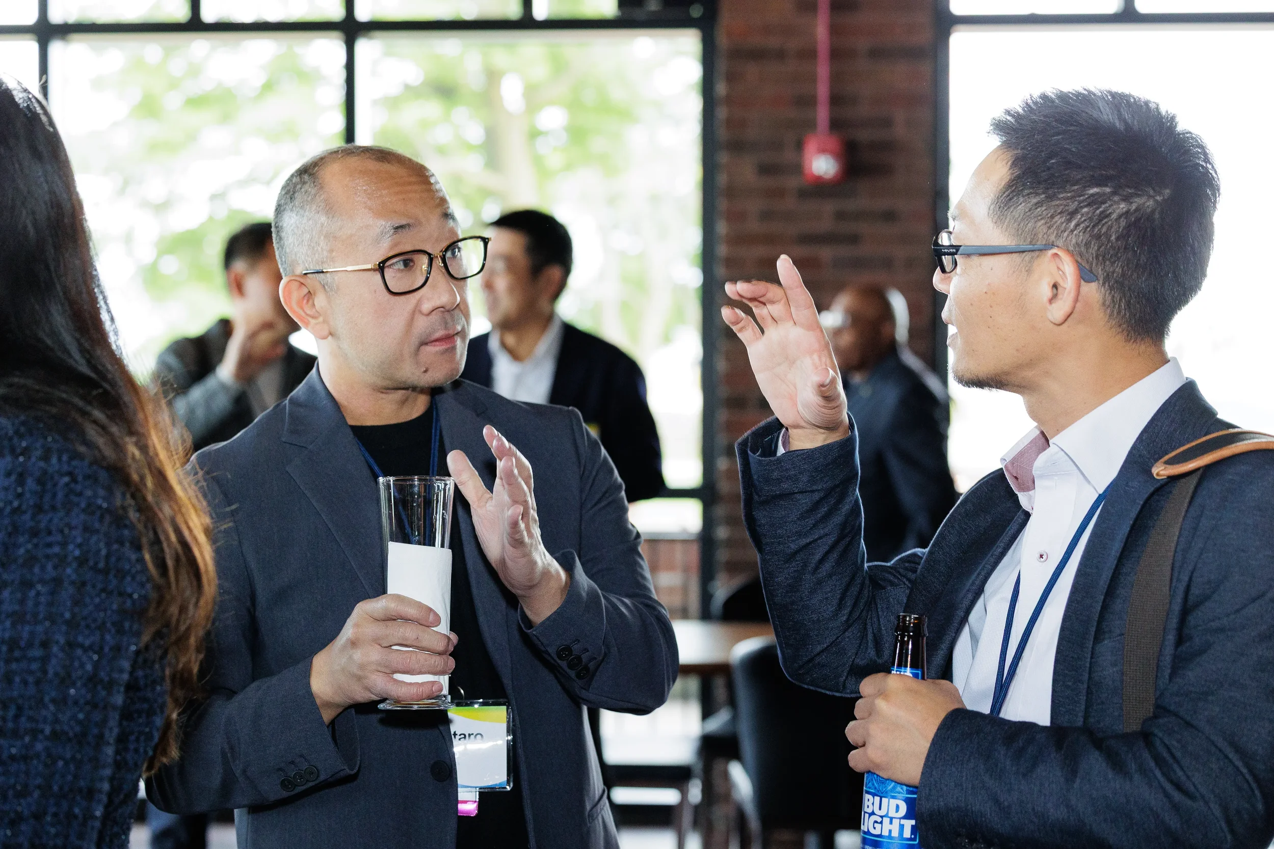 Two attendees in animated conversation with drinks at networking reception in Chicago brick venue
