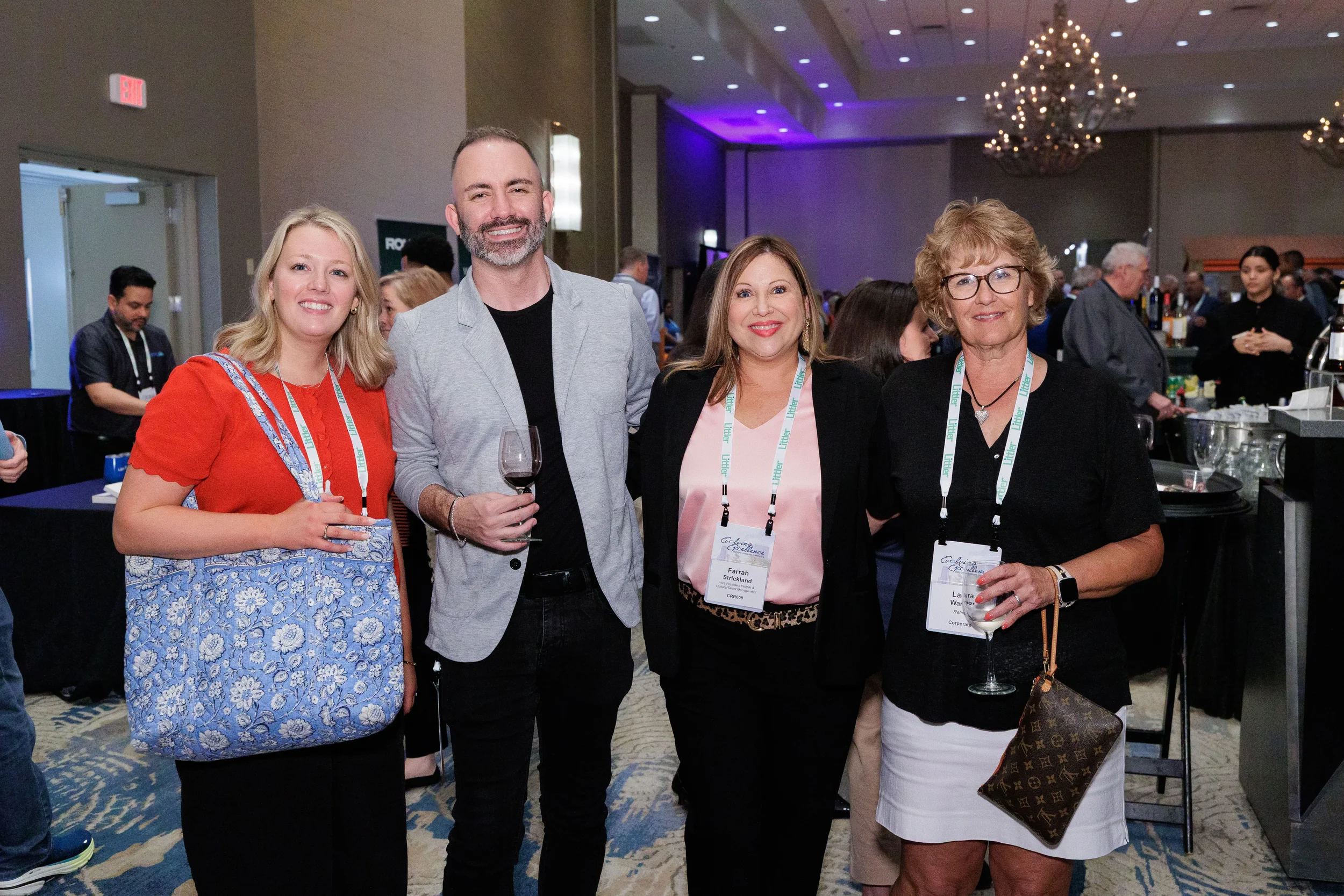Four attendees with lanyards pose together smiling at Orlando corporate conference evening reception