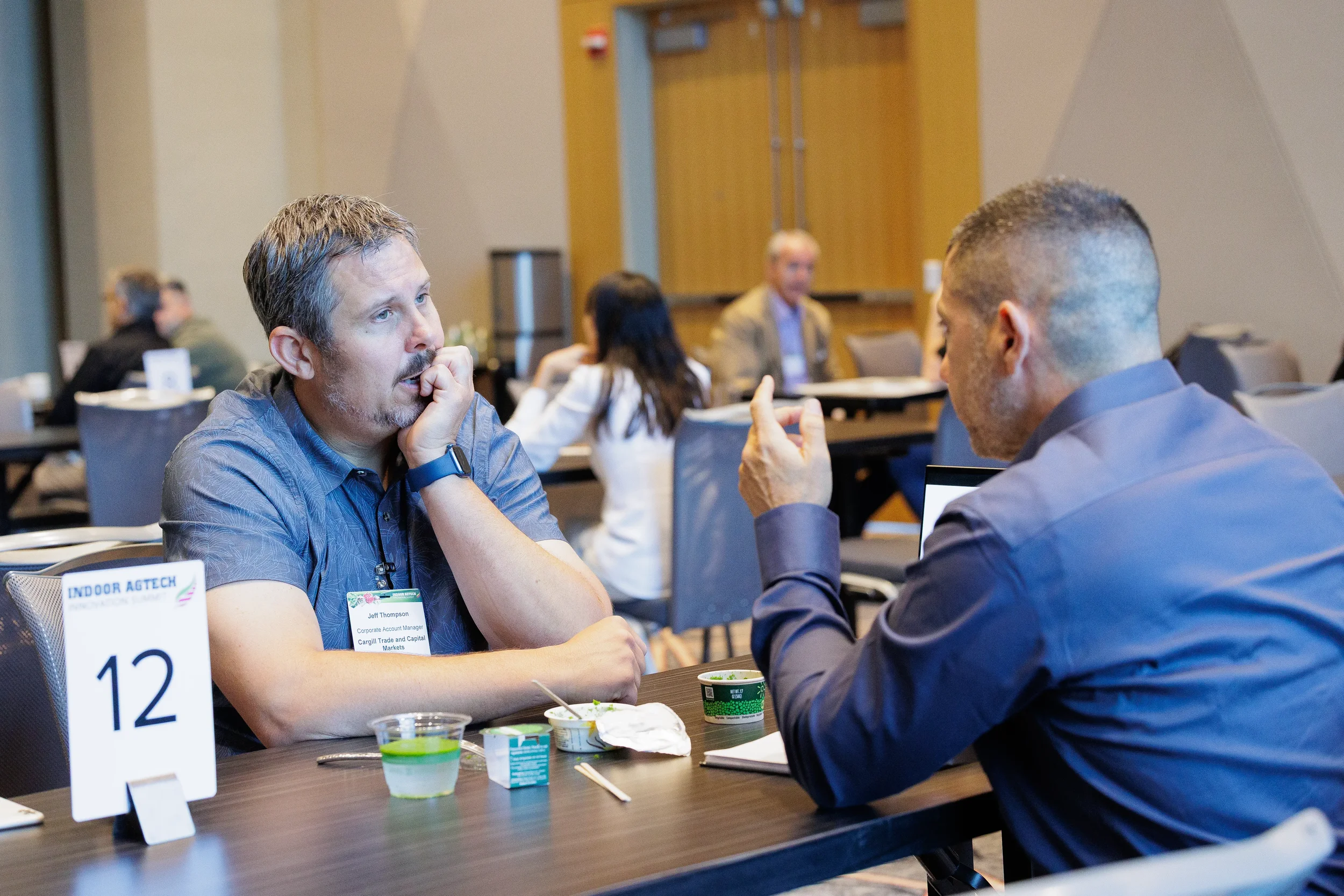 Two attendees engage in conversation at numbered table during Orlando conference session