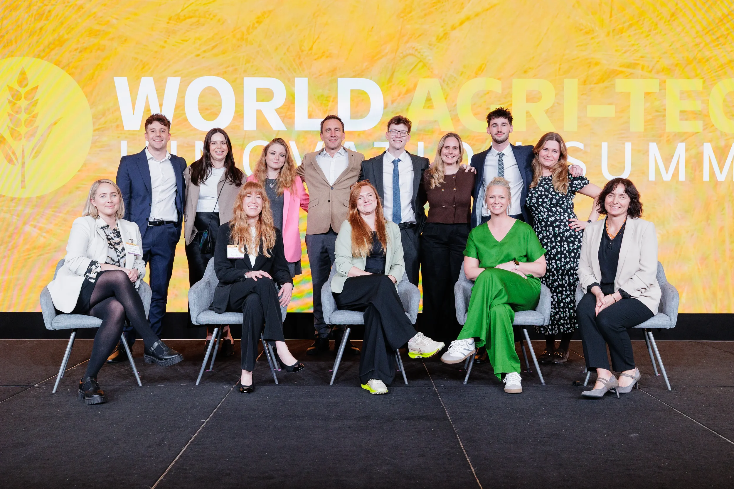 Large group poses for photo on stage in front of branded backdrop at Chicago corporate event