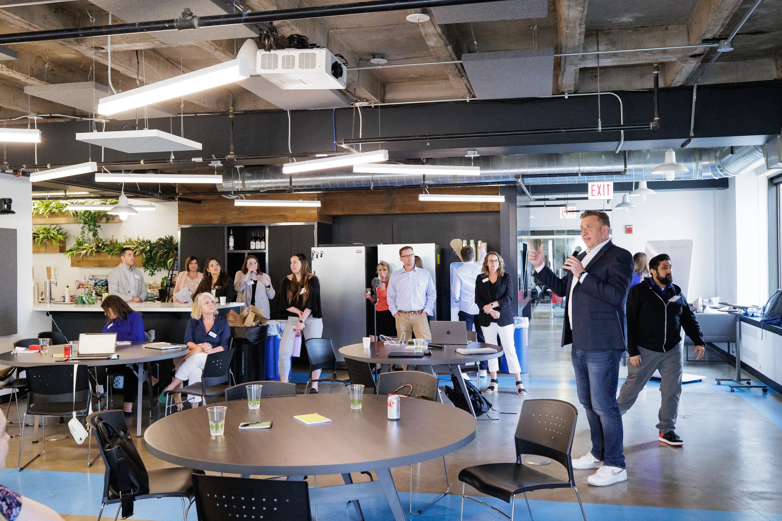 Male speaker addresses a mixed crowd of standing and seated attendees at Chicago corporate event venue