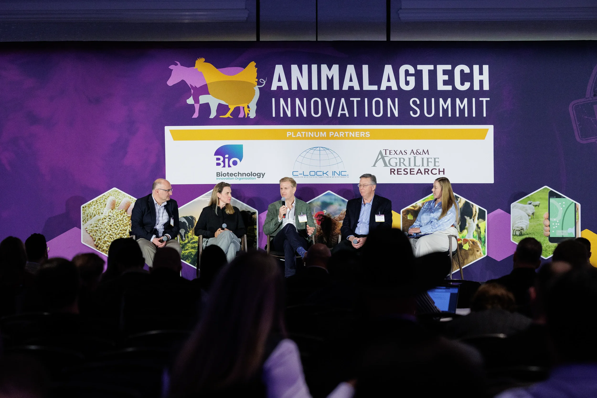 Five panelists seated on stage before full event banner at Orlando industry summit