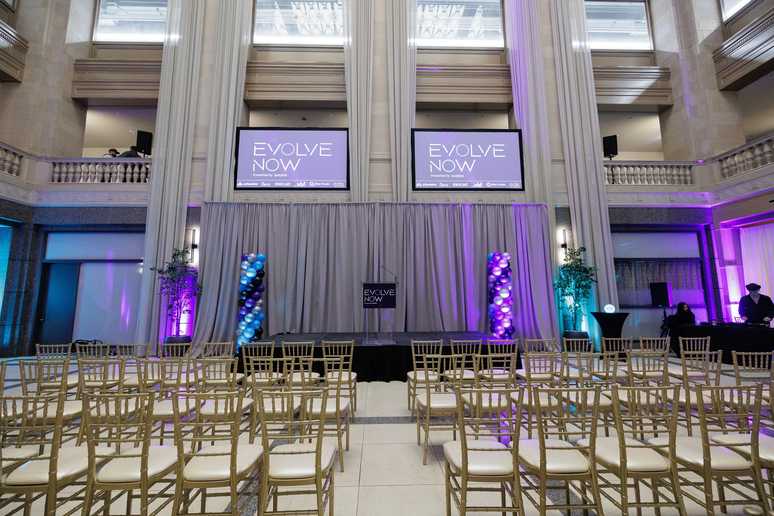 Elegant ballroom stage with podium and balloon columns set up for Chicago corporate event