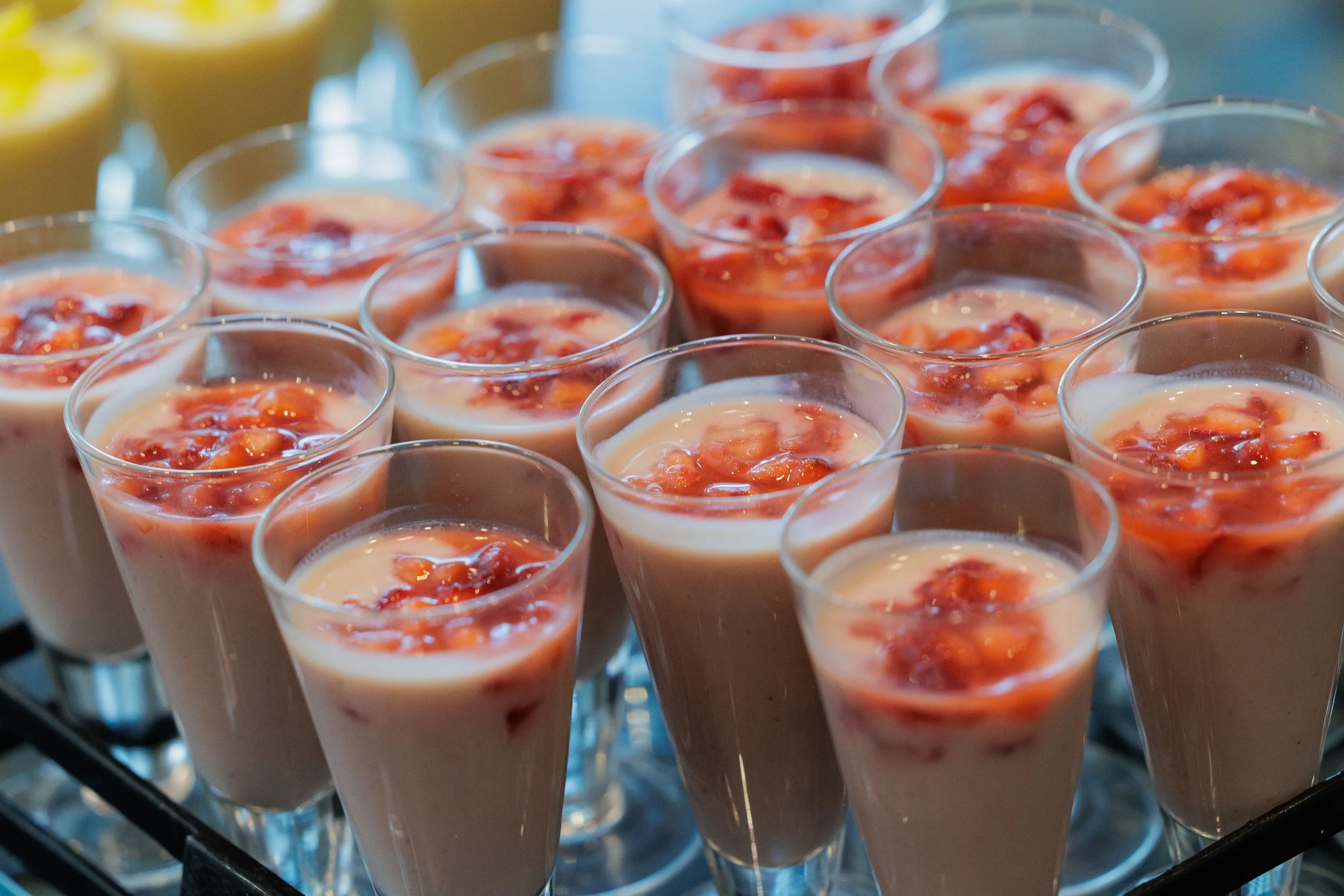 Rows of cream dessert cups topped with strawberry compote displayed at Orlando corporate event catering station