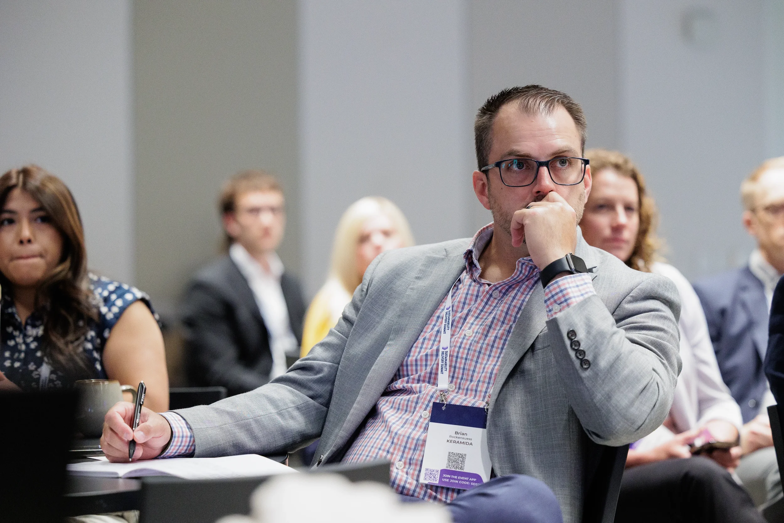 Attendee takes notes while listening intently during seated session at Orlando industry conference
