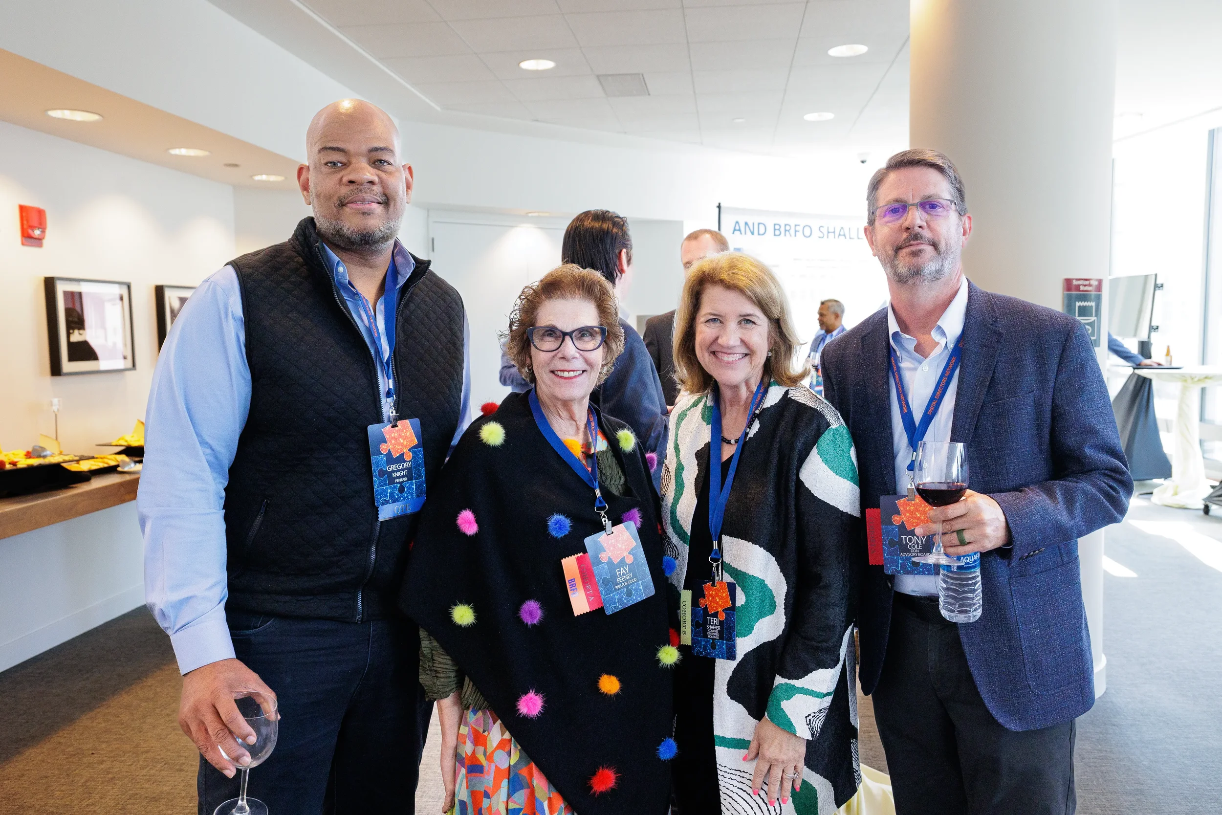 Four attendees with lanyards smile together during networking reception at Orlando corporate conference