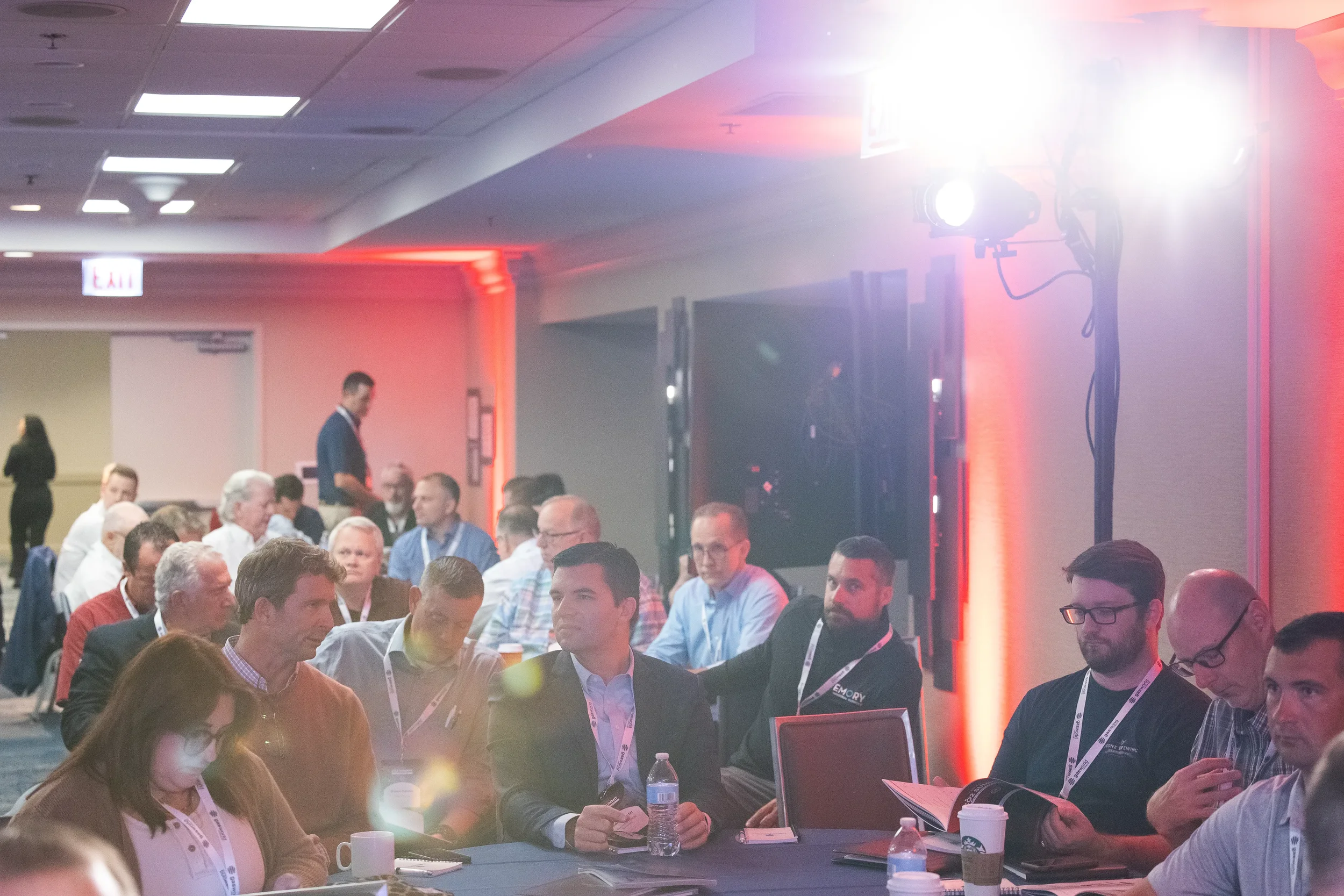 Packed audience of attendees watches stage under warm event lighting at Chicago industry conference