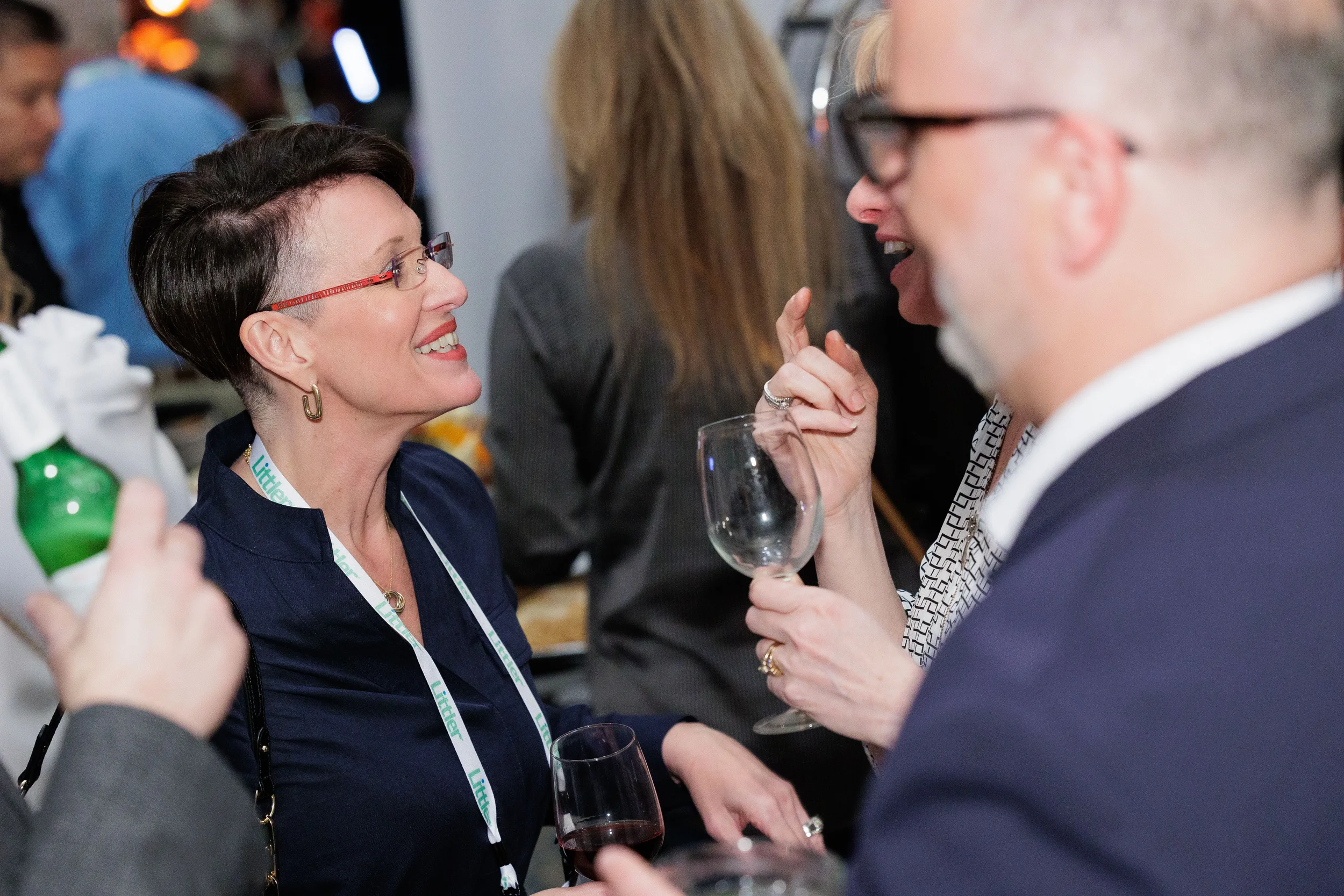 Female attendee with lanyard laughs while holding wine glass at Orlando corporate conference reception