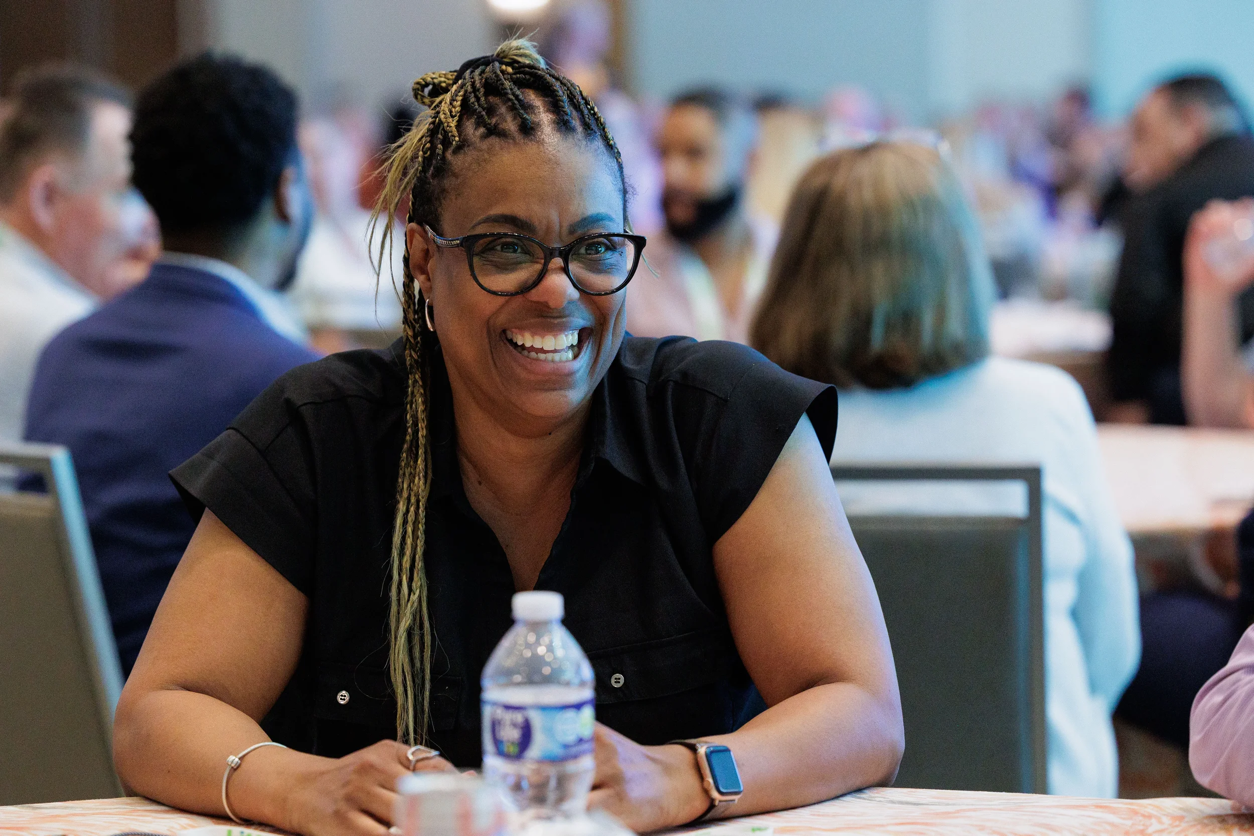 Attendee with glasses laughs warmly while seated at table during Orlando corporate conference session