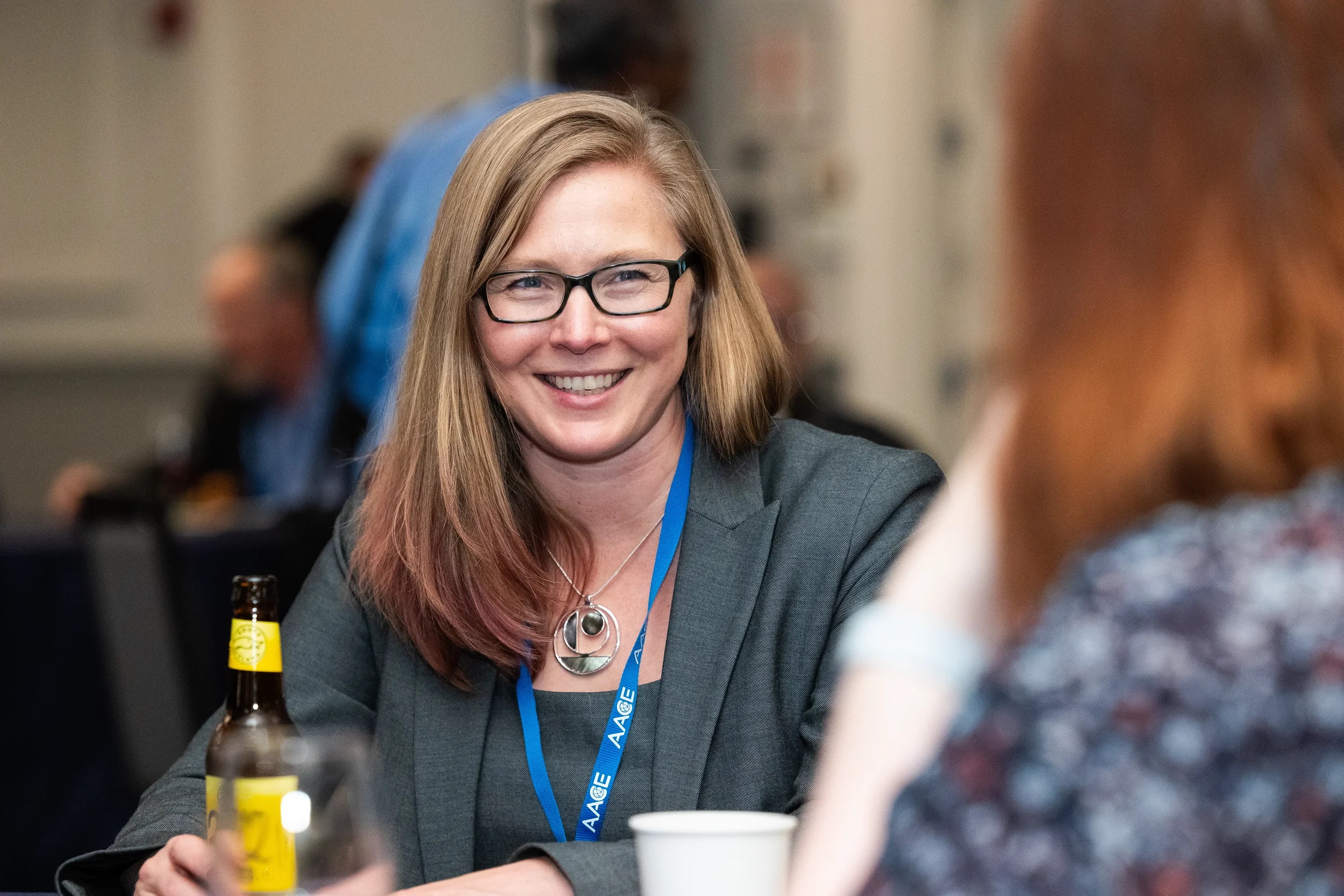 Woman in gray blazer enjoys conversation at AACE conference networking reception in Chicago
