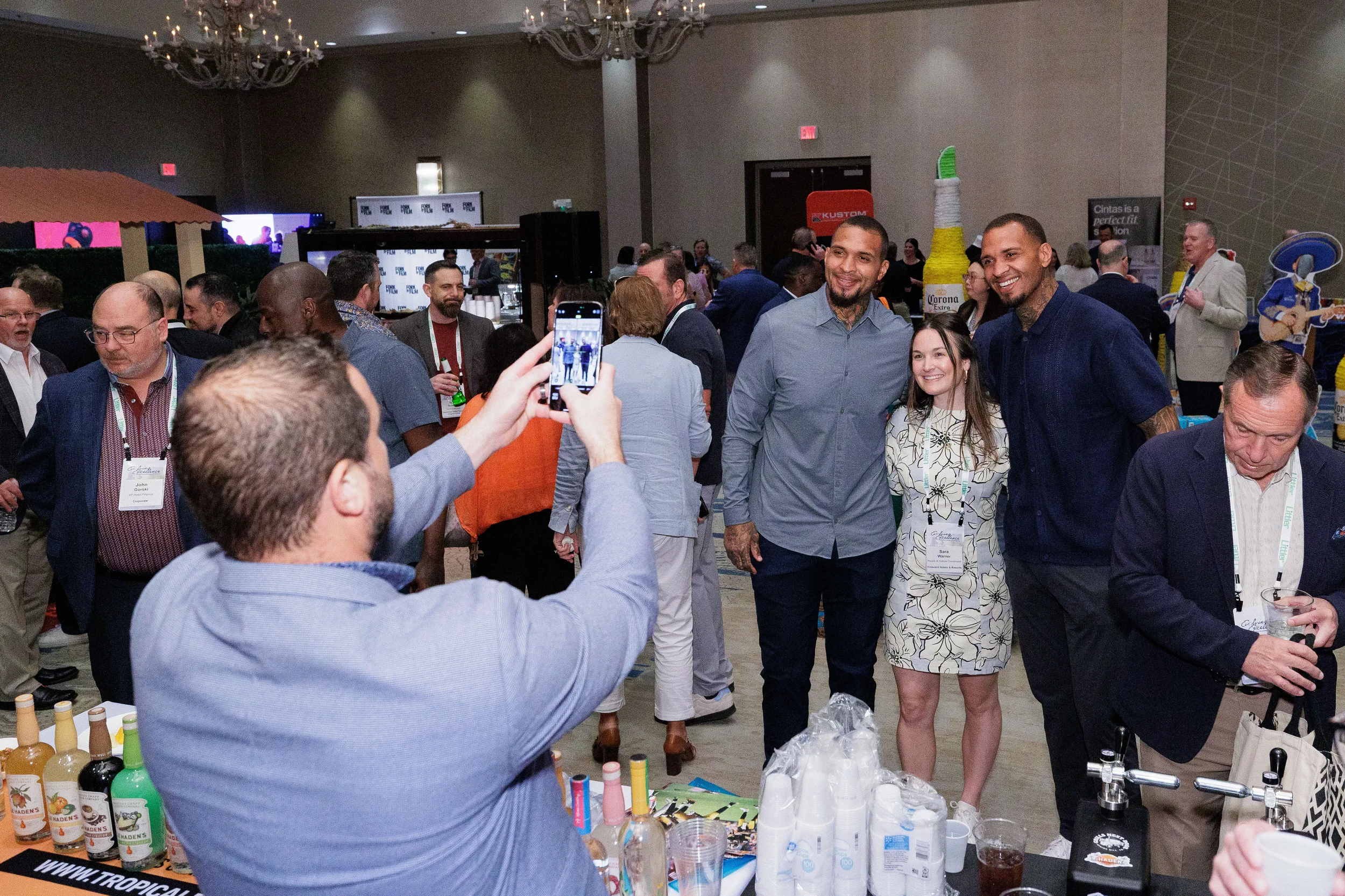 Attendee photographs group posing for photo on packed Chicago corporate conference expo floor