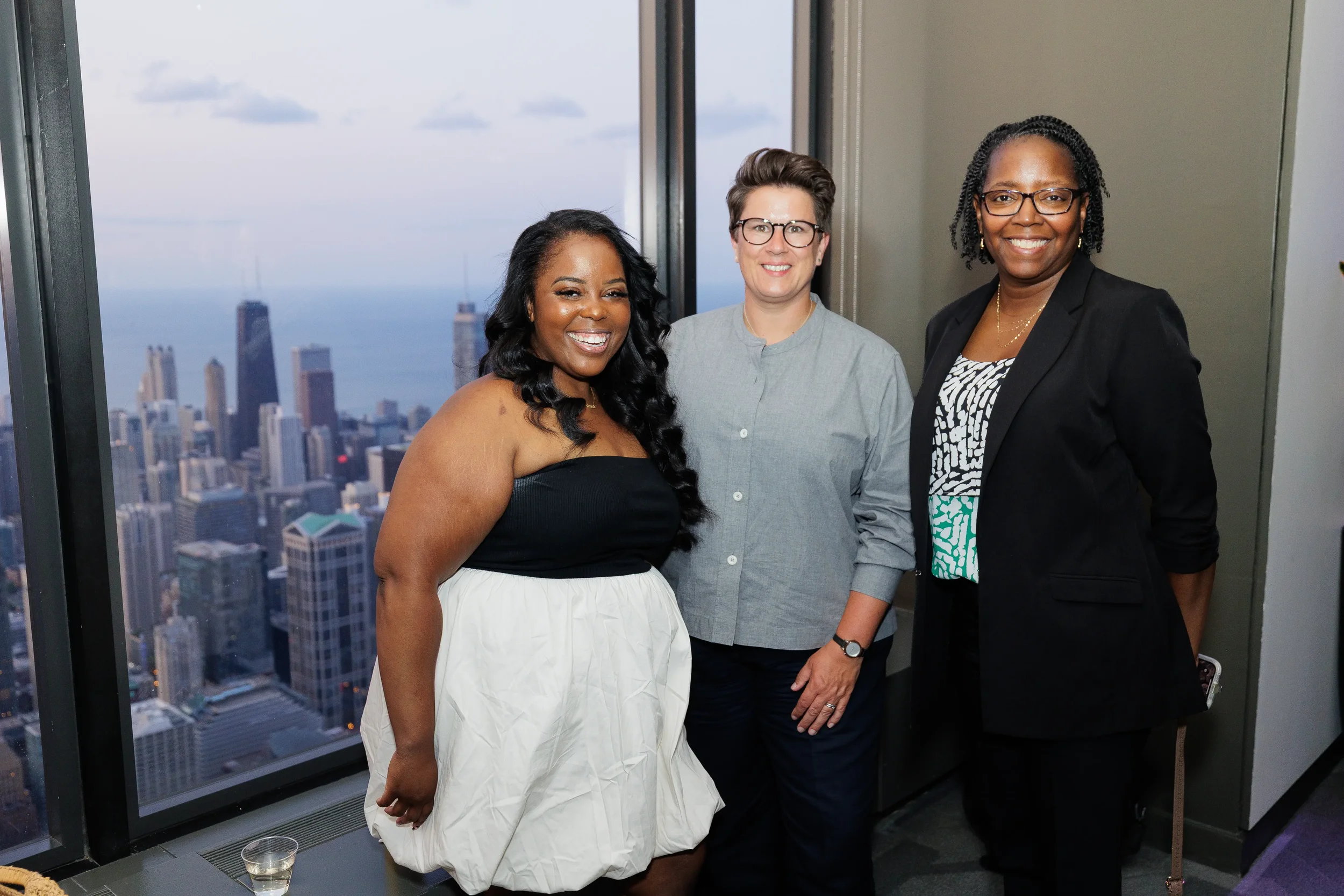 Three attendees pose together with skyline view during Orlando corporate event reception
