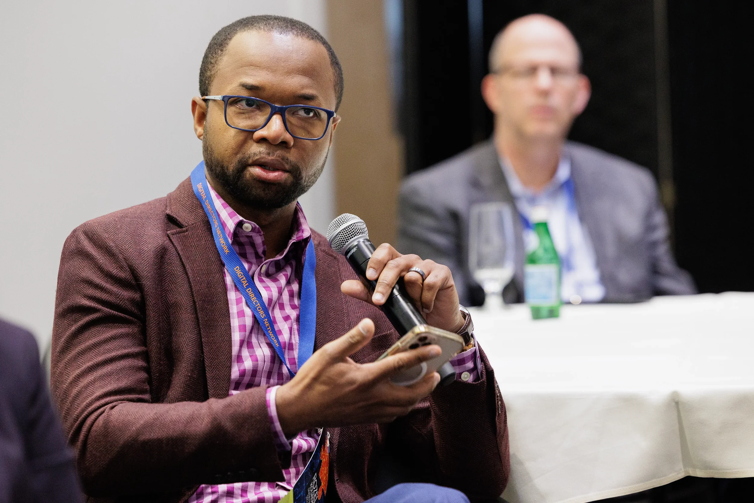 Male panelist with lanyard holds microphone while speaking during Orlando corporate conference session