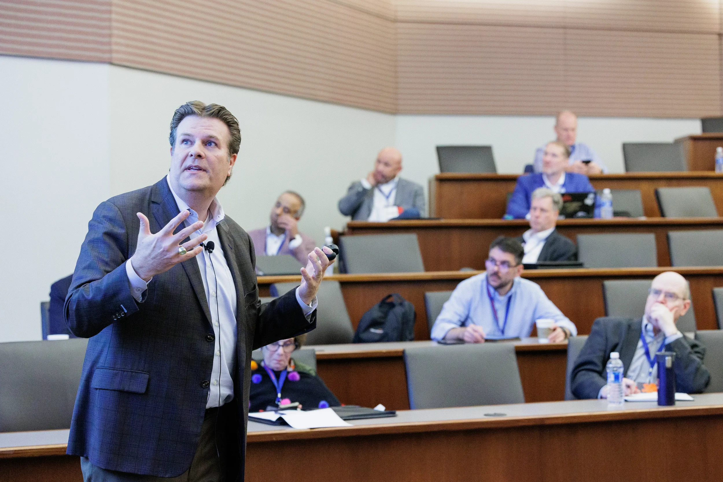 Speaker gestures expressively with both hands before tiered audience at Chicago industry conference