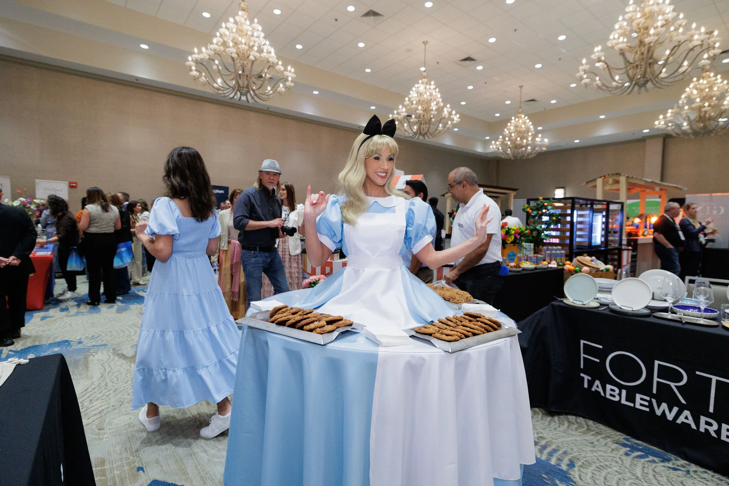 Costumed character poses at cookie display table in chandelier ballroom at Chicago corporate conference expo