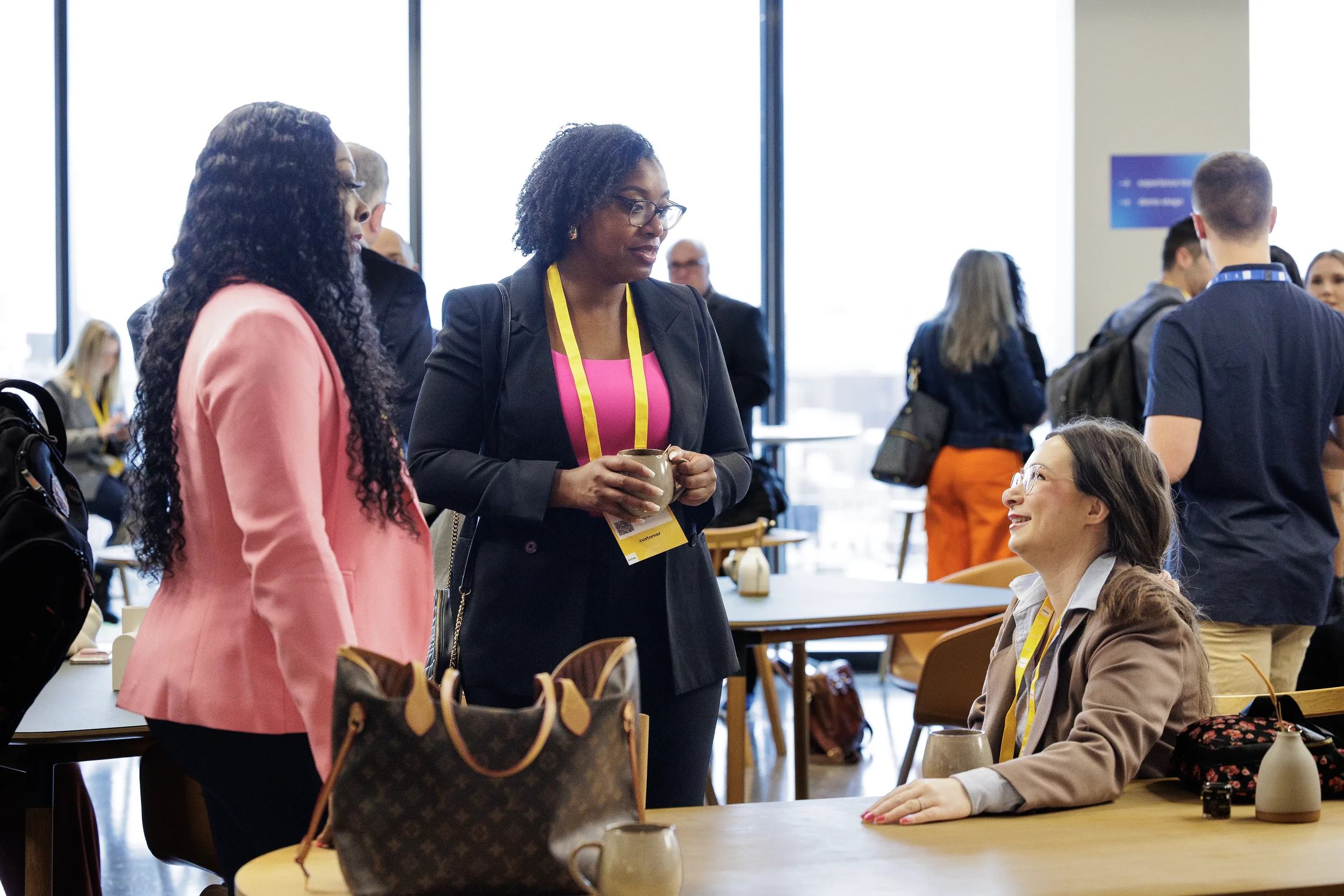 Attendees chat over coffee mugs near large windows in lounge at Chicago industry conference reception