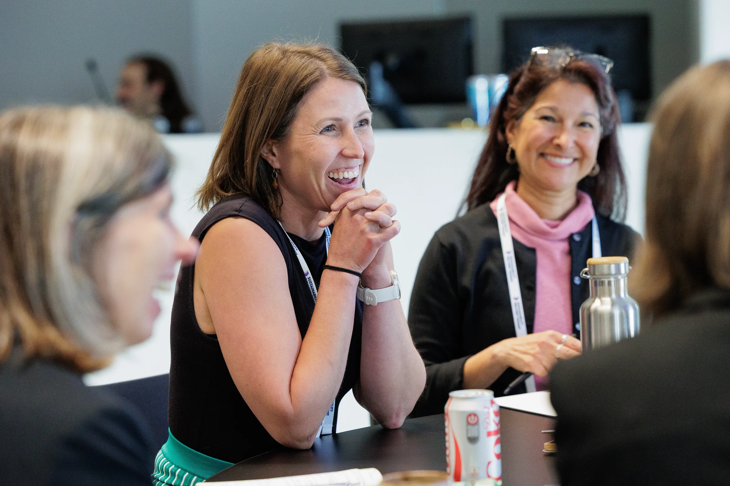 Attendees laugh together during conversation at standing table at Chicago corporate conference