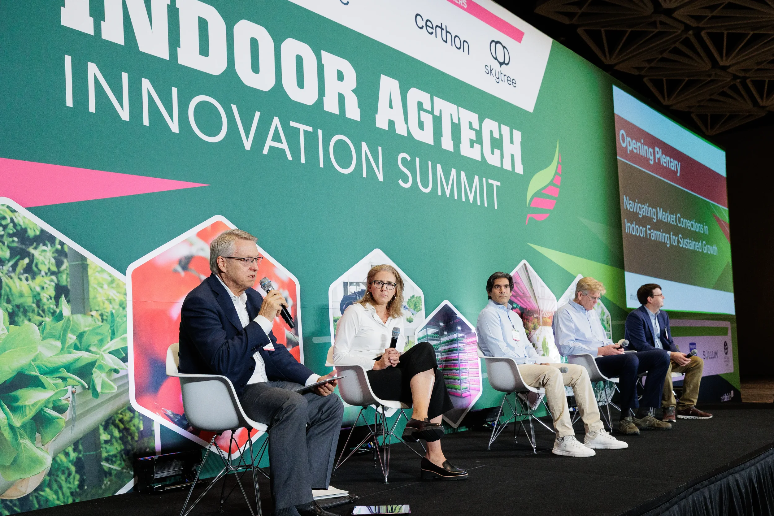 Moderator speaks into microphone while leading panel discussion on stage at Chicago industry summit