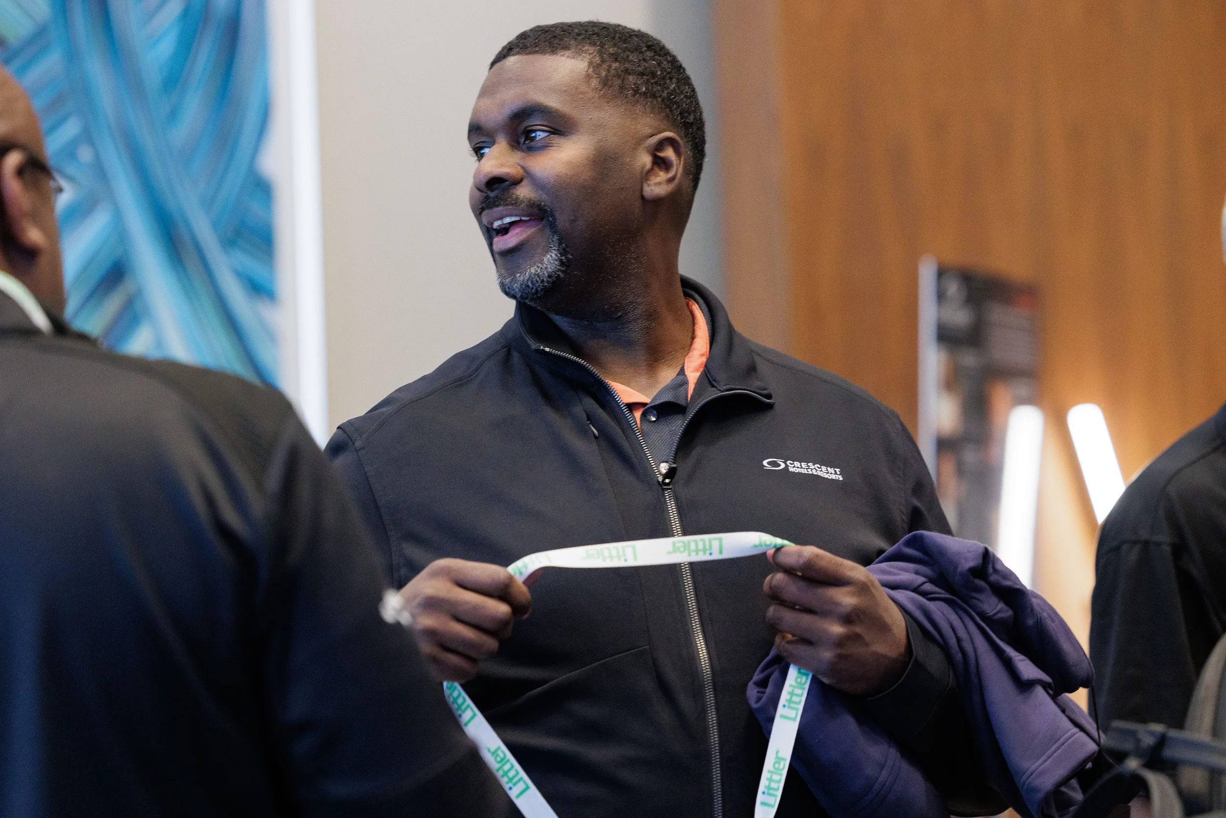 Male attendee with lanyard adjusts badge while conversing at Chicago industry conference