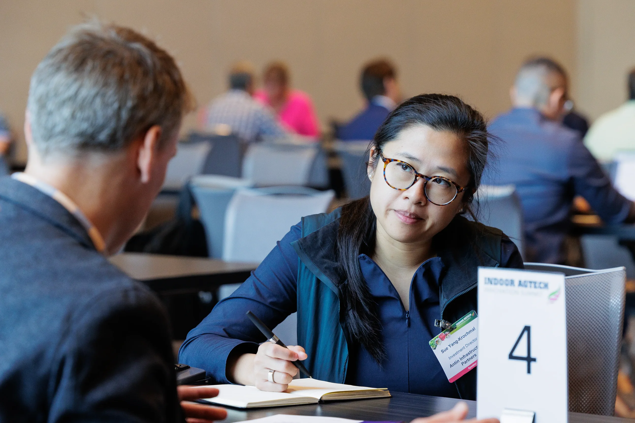 Attendee takes notes during focused one-on-one meeting at numbered table during Chicago industry conference