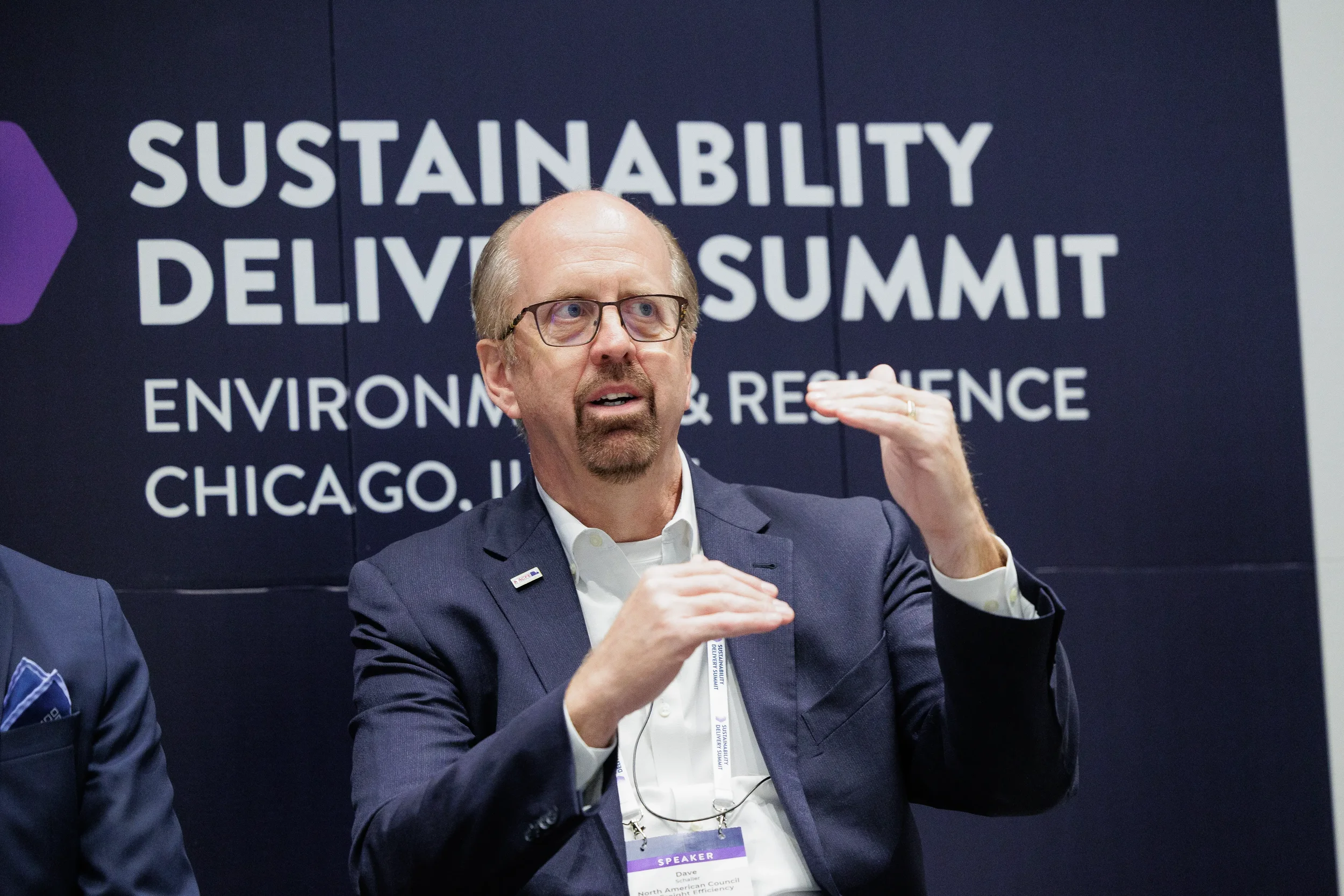 Panelist gestures while speaking on branded stage at Orlando industry conference