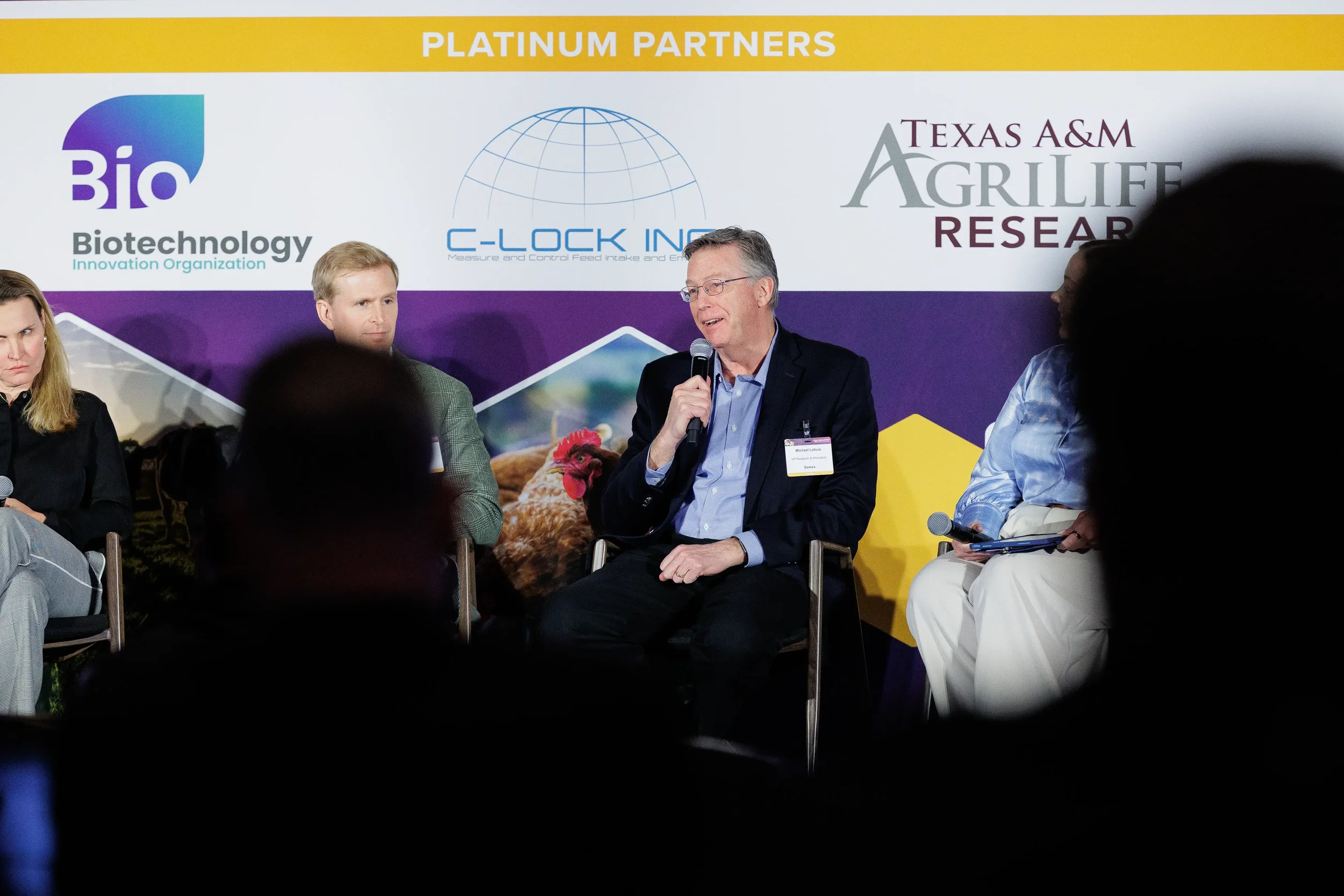 Panelist speaks into microphone during four-person panel discussion at Chicago industry summit