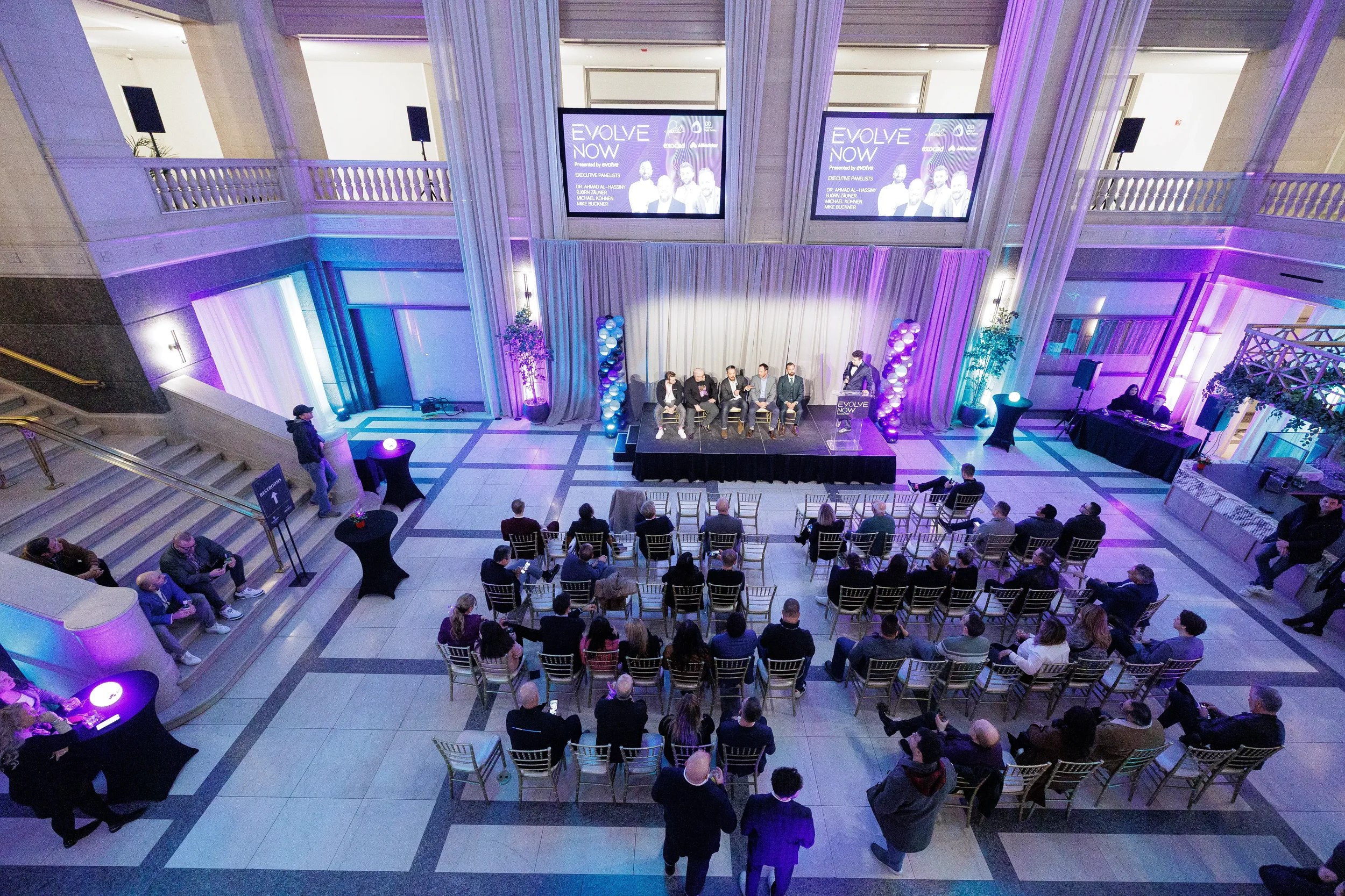 Overhead view of panel on stage with full audience seated in grand Chicago corporate event venue